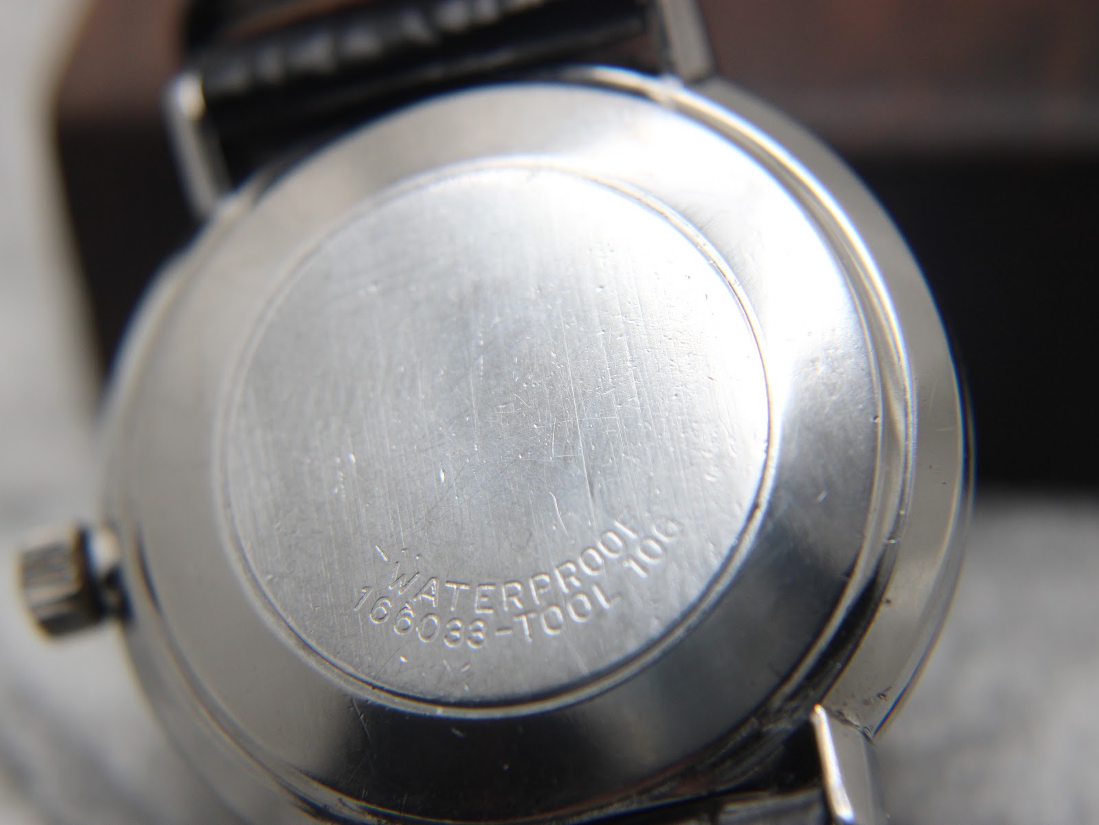 Close-up of the solid stainless steel case back of the Omega De Ville, with "WATERPROOF" and reference number "166033-TOOL 106" engraved.