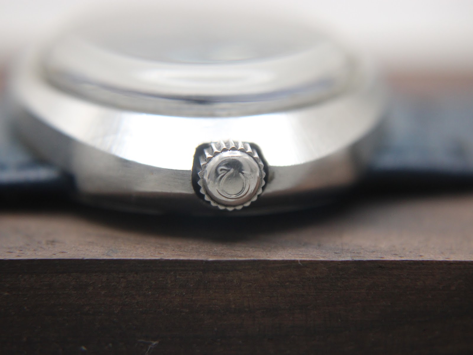 Detailed close-up of the original signed Omega crown on the side of the watch case, showing the Omega symbol.
