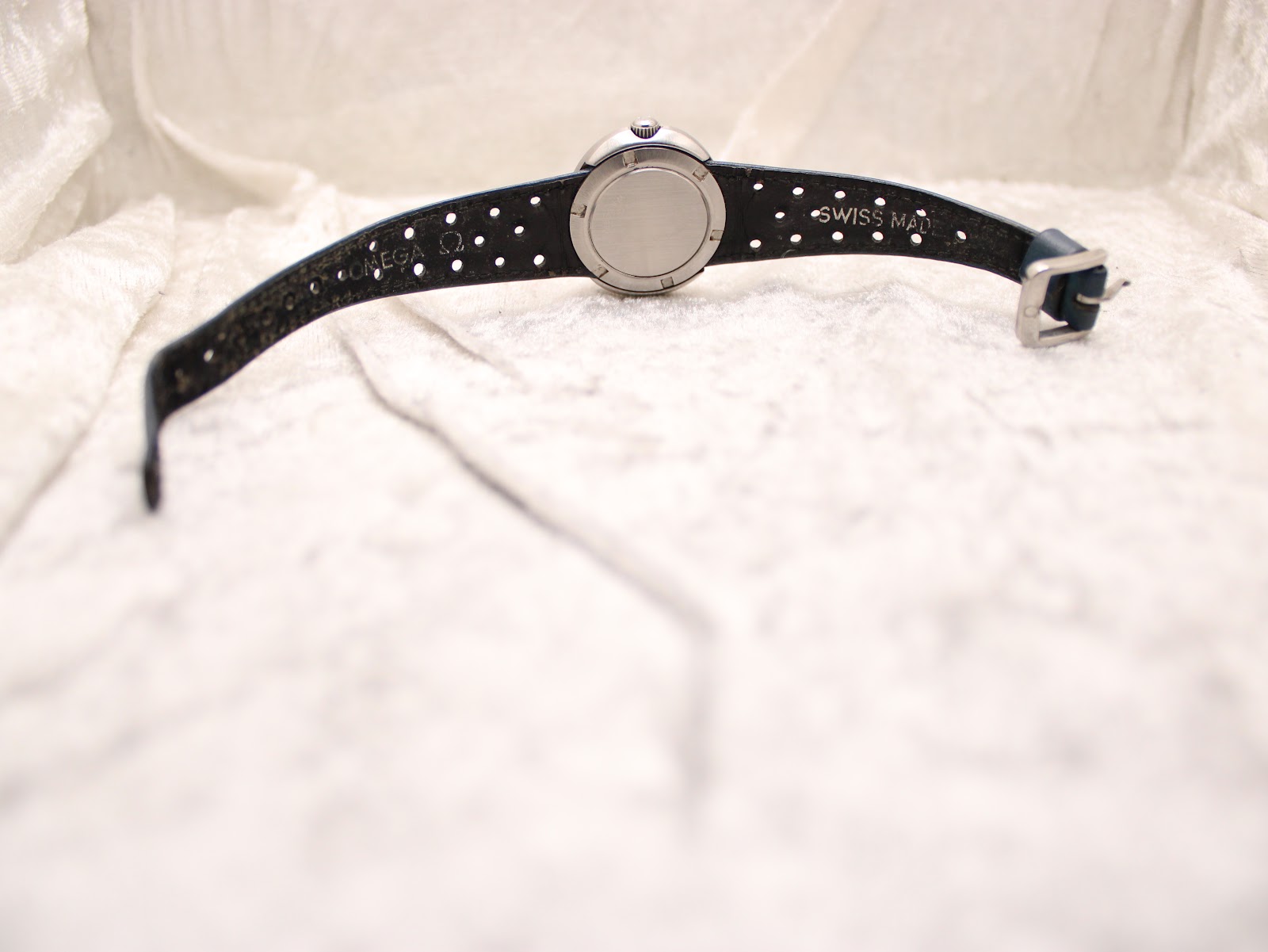 Rear view of the Omega Genève Dynamic watch, showing the case back and the full length of the blue perforated racing strap with buckle.