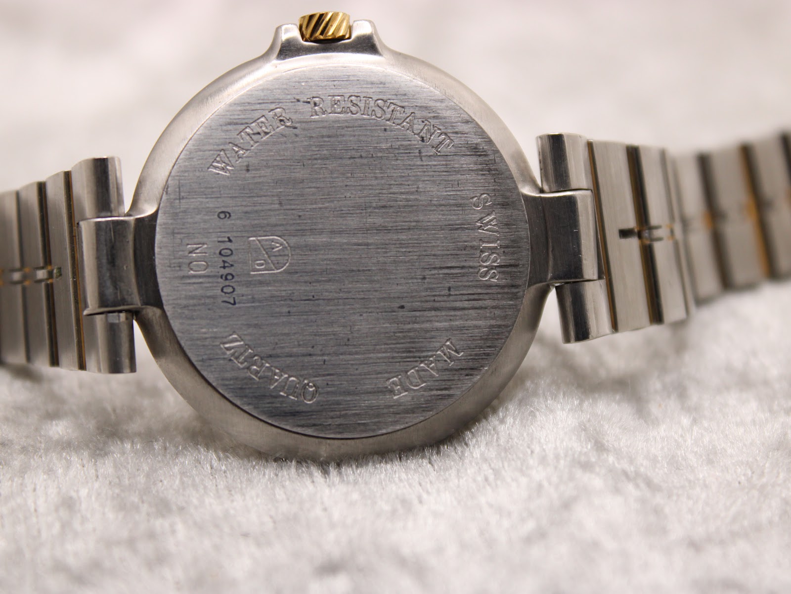 Close-up of the brushed stainless steel case back with "Water Resistant Swiss Made Quartz" engraving and serial number.