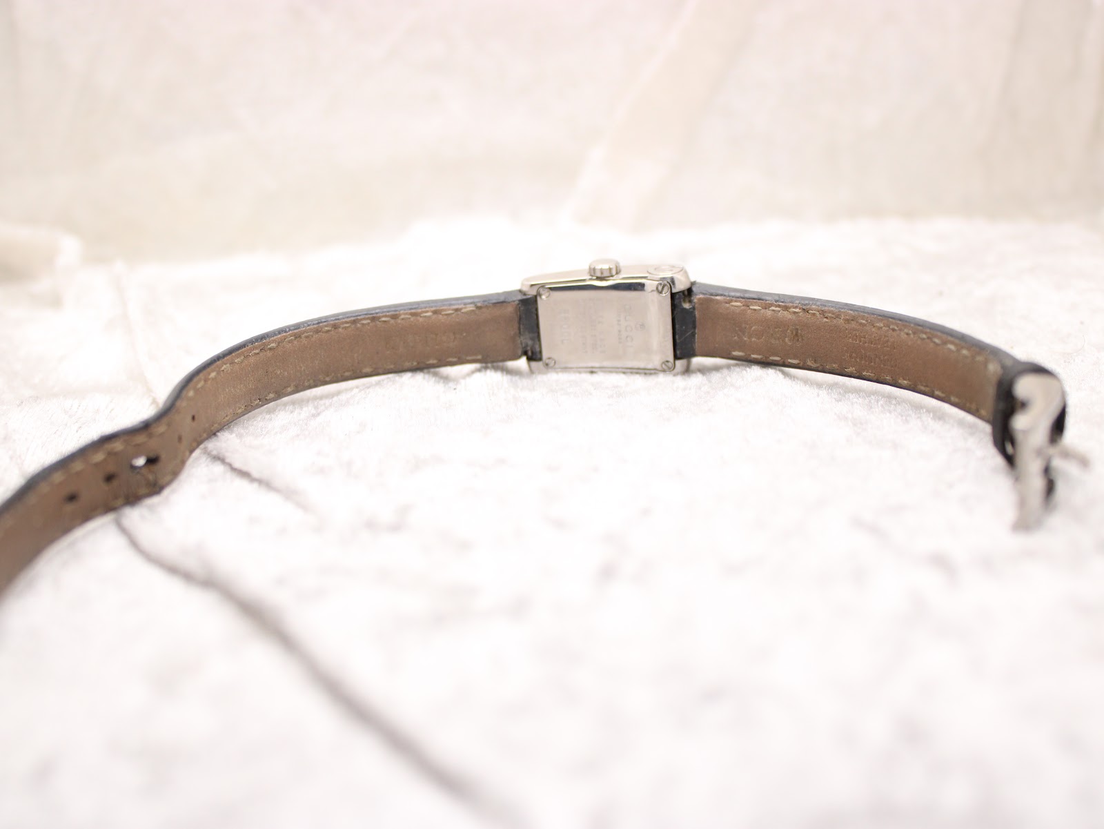Back view of the Gucci 8600L watch, showing the stainless steel case back and the underside of the worn black leather strap.
