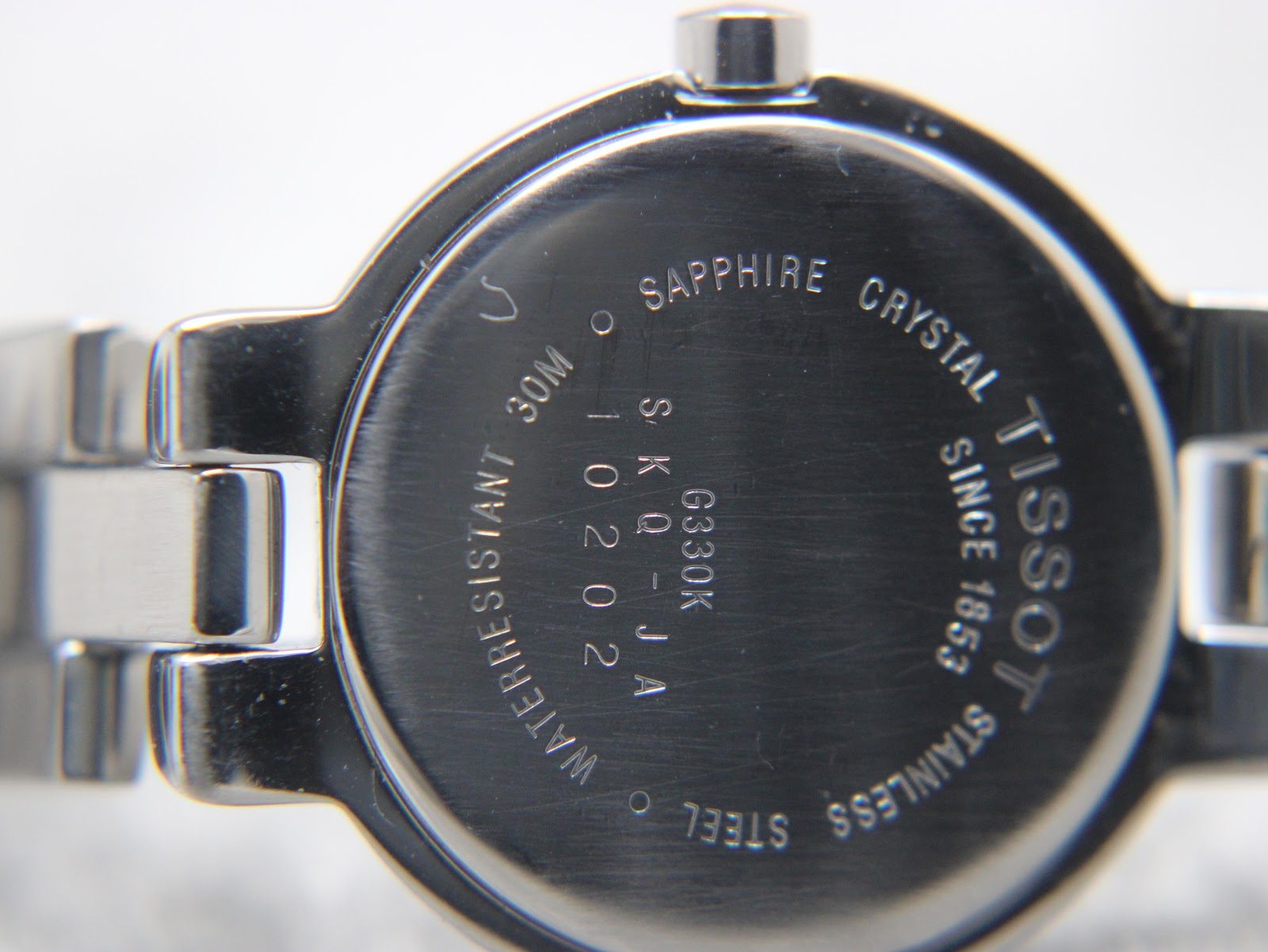 Close-up of the case back showing 'Tissot since 1853', 'Sapphire Crystal', 'Stainless Steel', '30M Water Resistant' and model 'SKQ-JA G330K'.