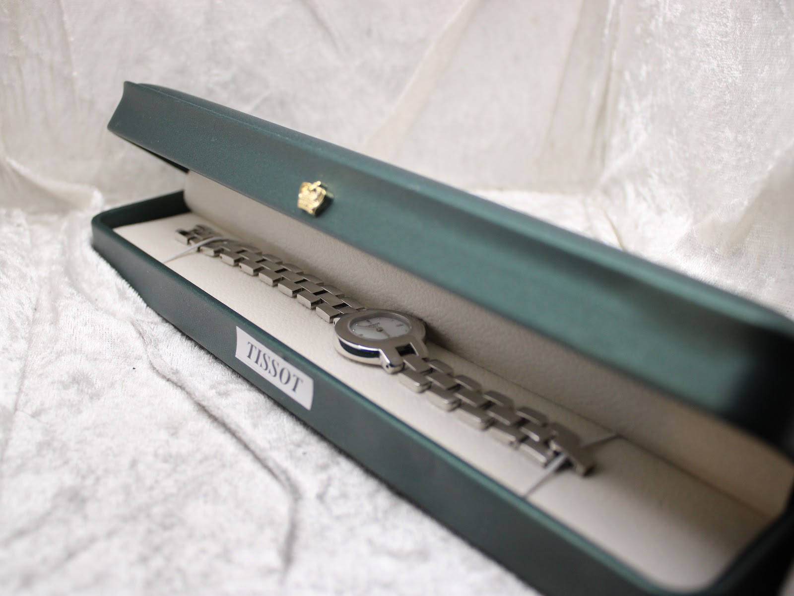 The Tissot watch displayed in an open green presentation box, showing the bracelet and dial.
