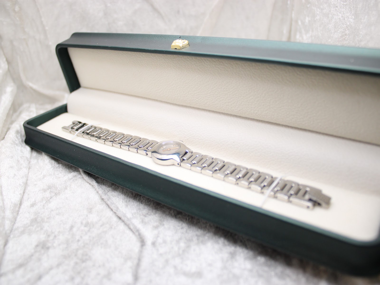 Tissot watch and bracelet presented inside a green rectangular watch box.