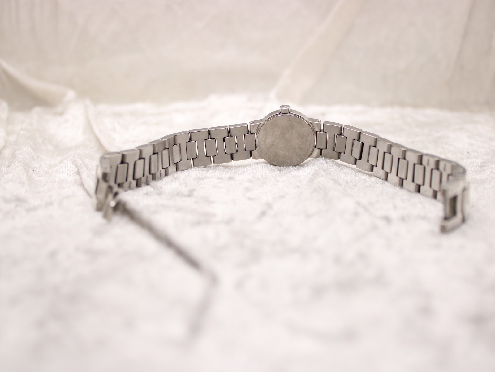 Rear view of the Tissot watch and bracelet laid flat, showing the case back and fully extended bracelet.