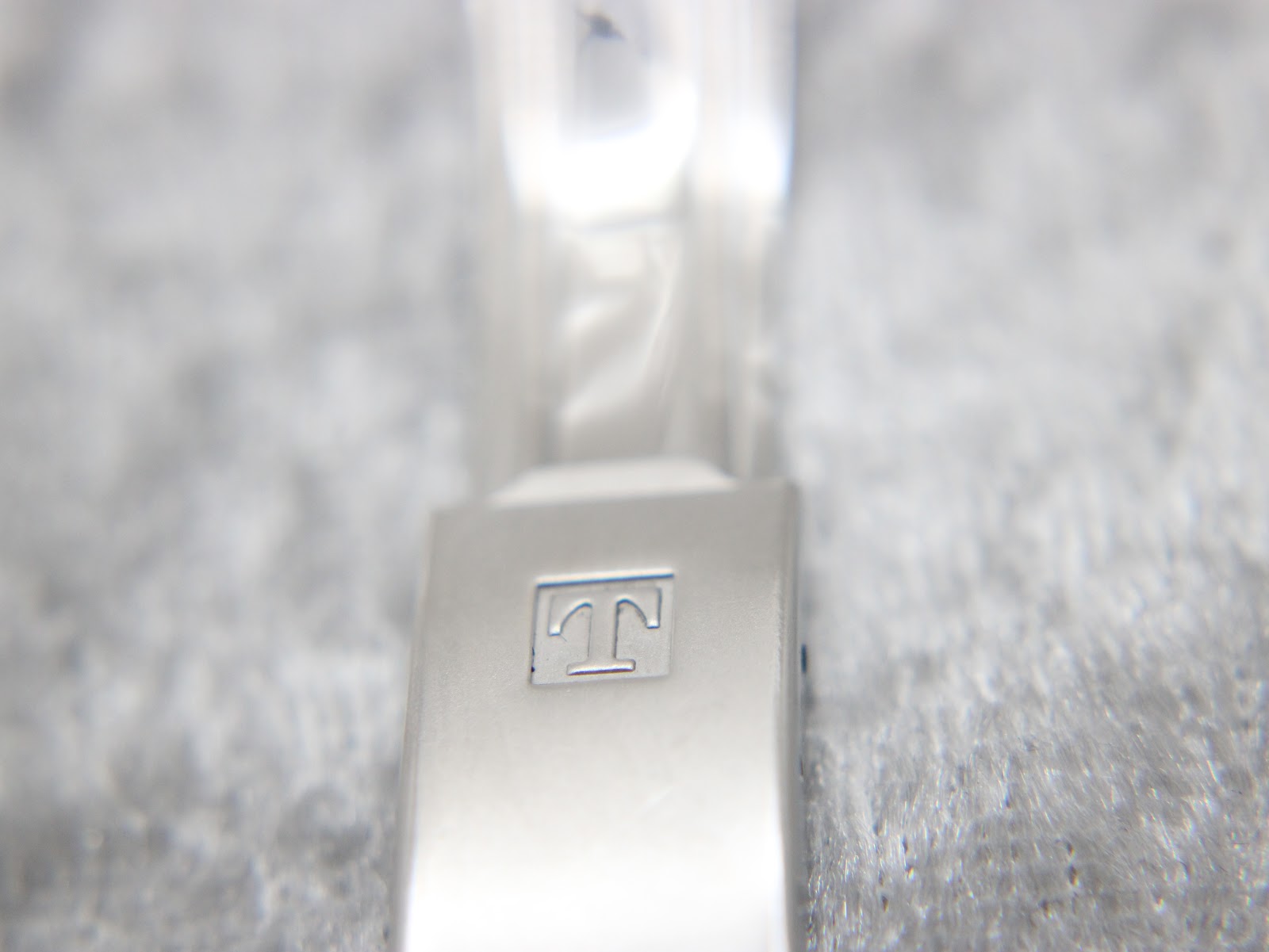Detailed close-up of the Tissot signed fold-over clasp on the two-tone watch bracelet.