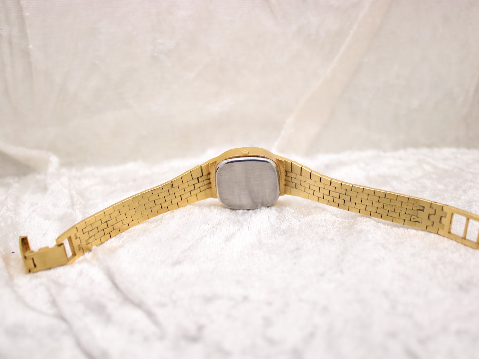 Back view of the vintage Tissot watch, showing the plain, brushed case back and the integrated gold tone bracelet.