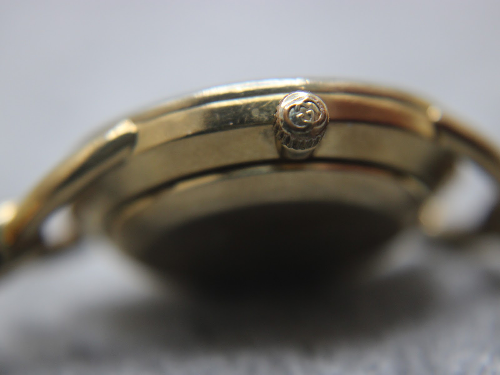 Macro shot of the original signed Gucci crown, detailing its textured finish and logo.