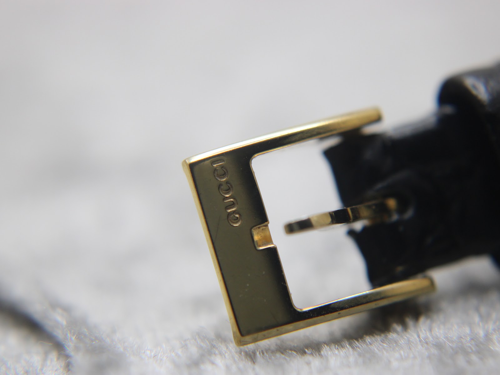 Close-up of the gold-tone buckle, clearly engraved with the "GUCCI" brand name.