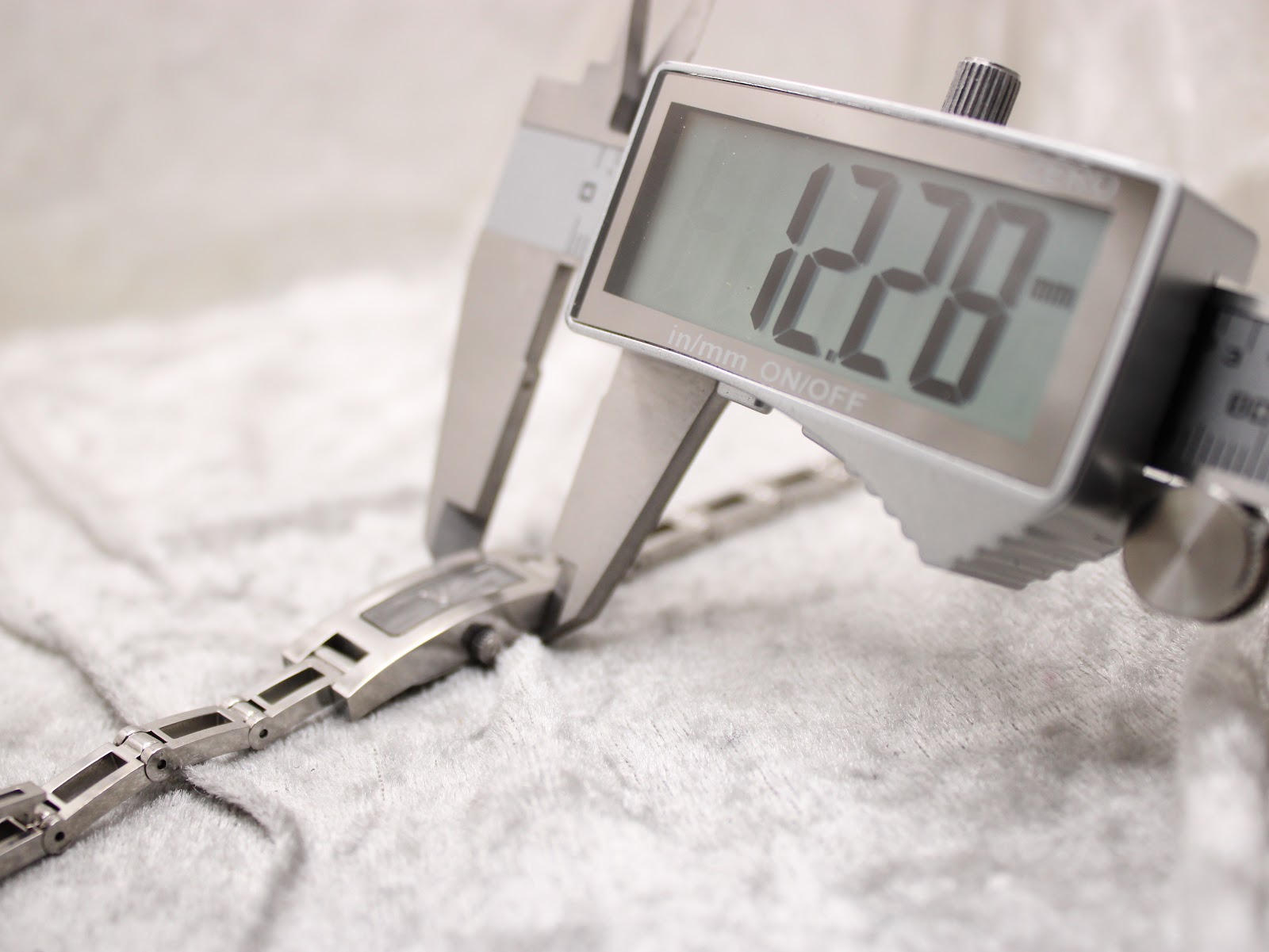 Digital caliper measuring the case width of the Gucci 3900L, displaying 12.28mm.