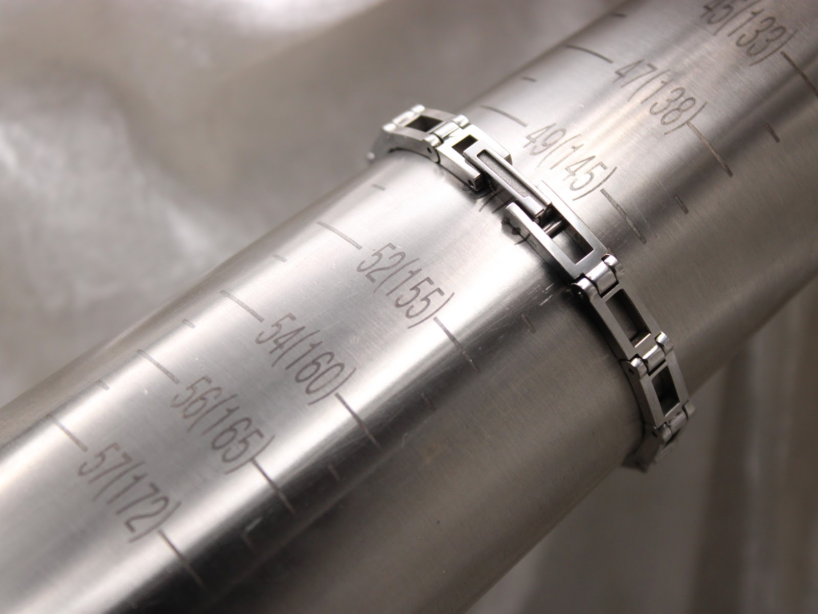 The stainless steel Gucci bracelet being measured on a wrist sizing mandrel, showing a fit of 155mm.
