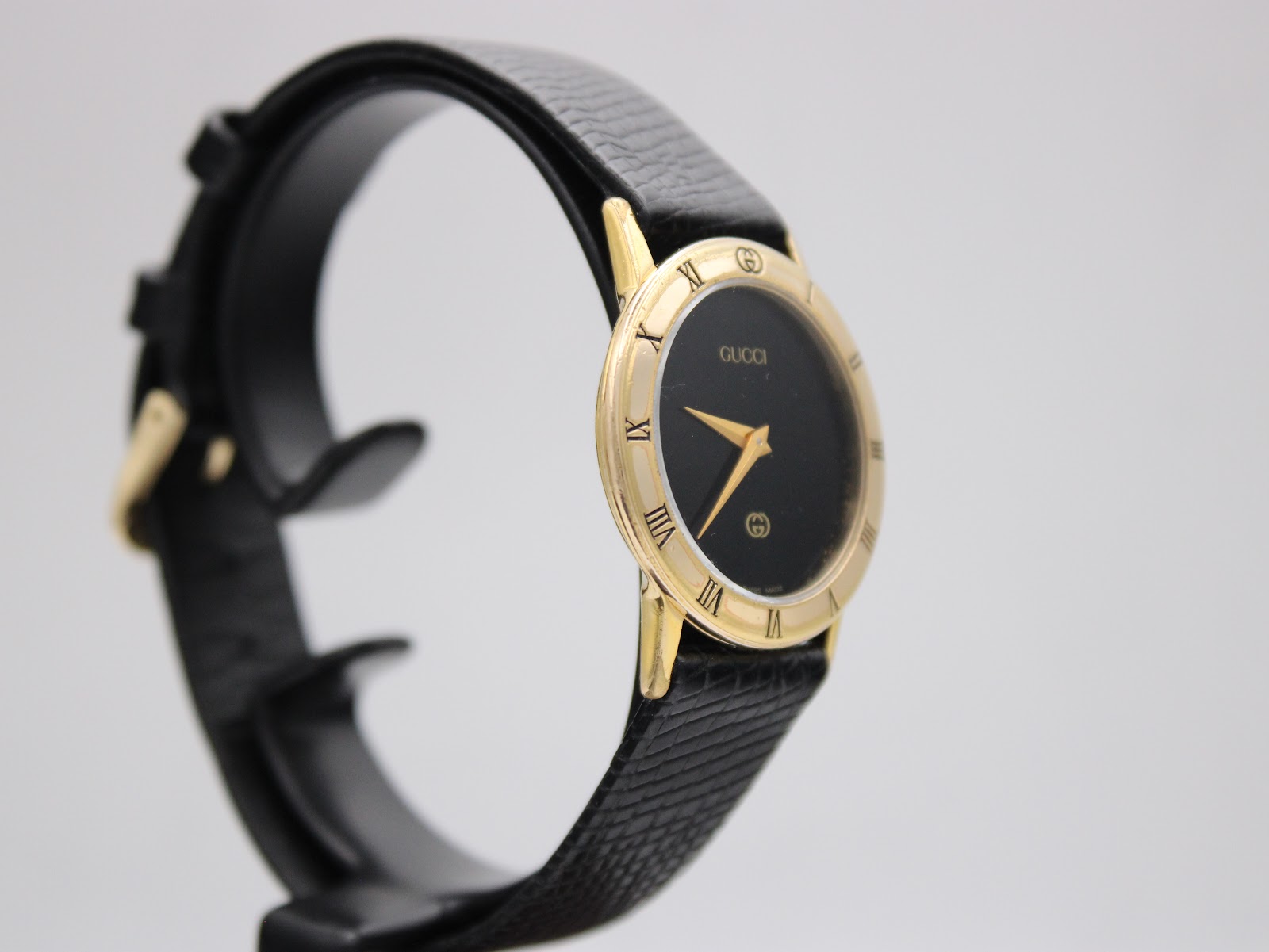 Left-side view of the gold-plated Gucci 3000 Jr watch on a display stand, highlighting the case profile.