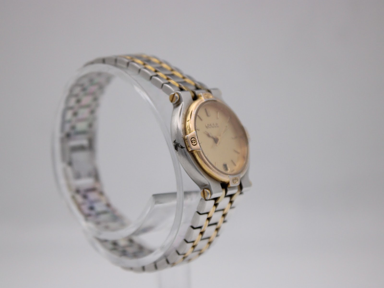 Another side view of the Gucci 9000 L watch, highlighting the curved case and the two-tone bracelet links.
