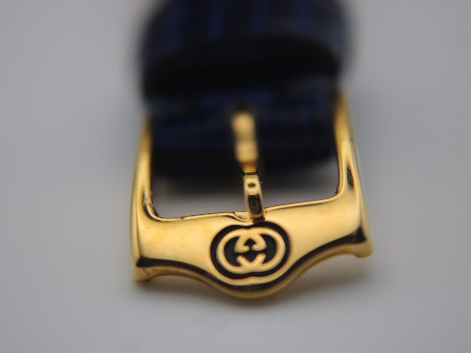 Close-up of the gold-tone buckle with an engraved Gucci interlocking G logo.