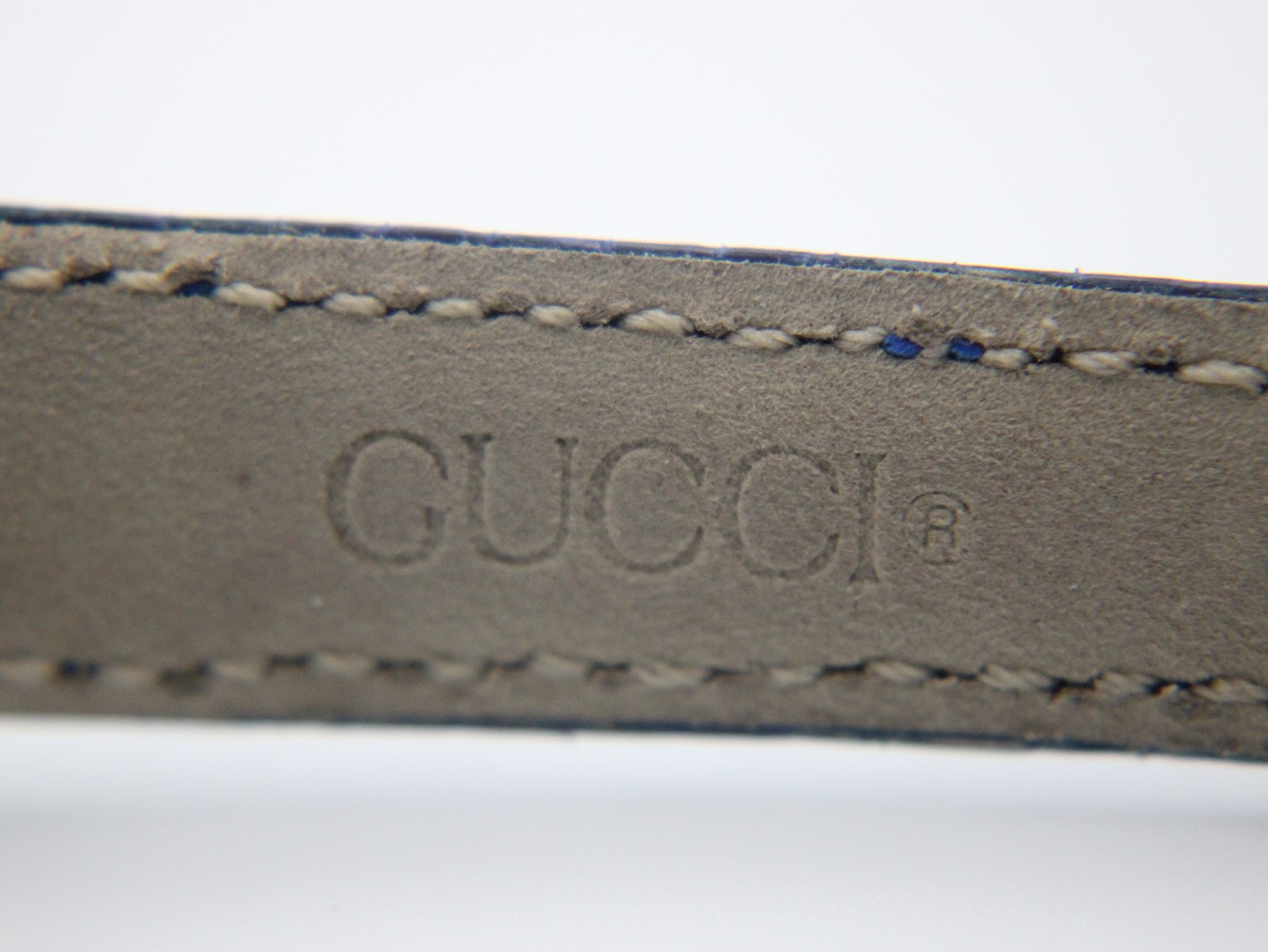 Close-up of the blue leather strap interior showing the embossed 'GUCCI®' logo.