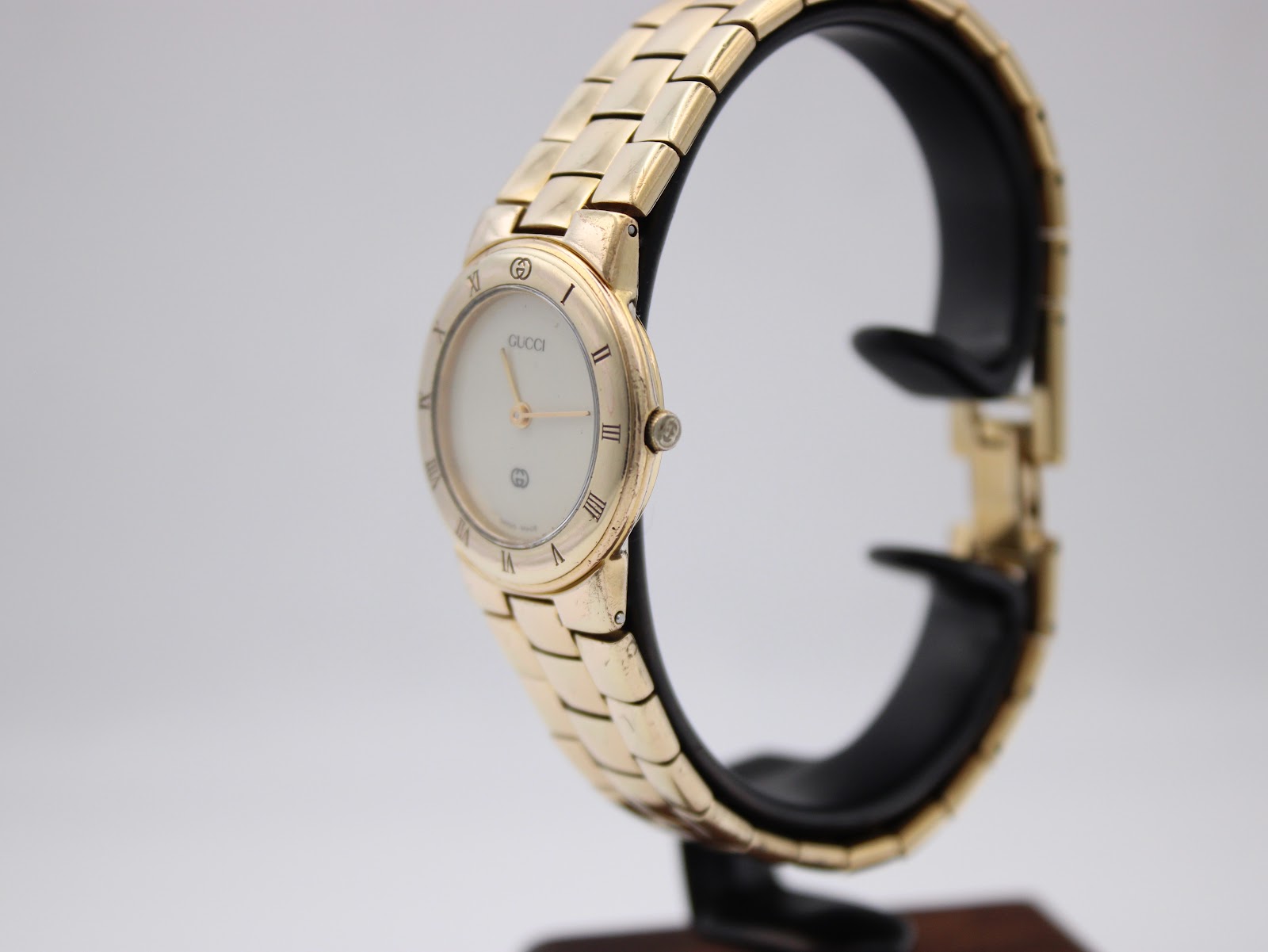 Angled side view of the Gucci 3300L watch displayed on a stand, highlighting the case profile and bracelet links.