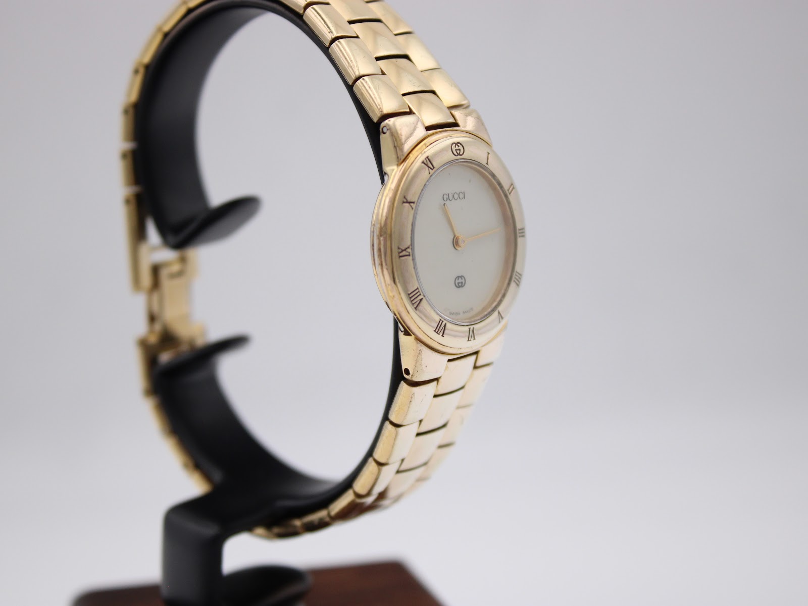 Three-quarter view of the Gucci 3300L watch on a display stand, showcasing the dial, crown, and bracelet.