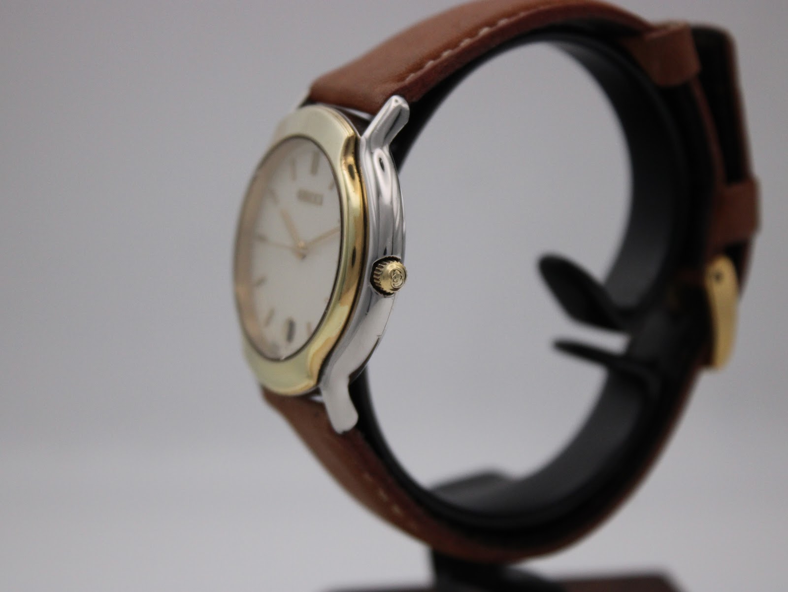 Side view of the Gucci watch showing gold-tone crown and two-tone stainless steel case.