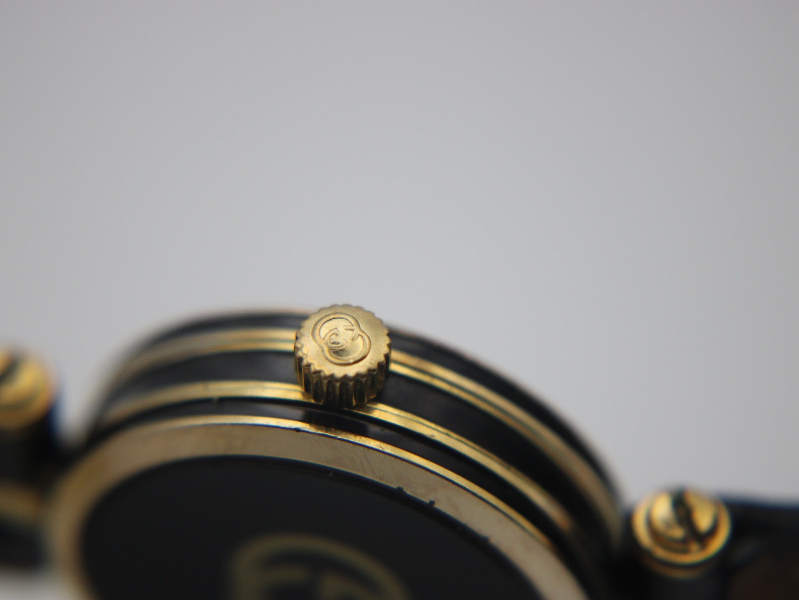 Close-up of the original Gucci signed crown on the gold-tone watch case.