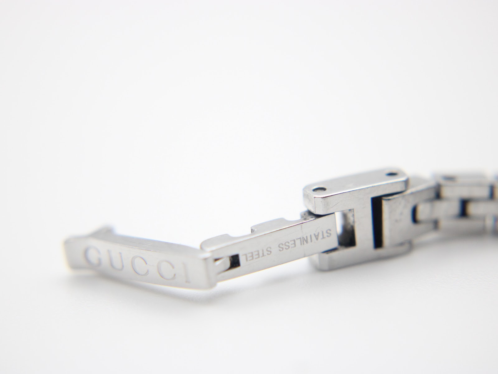 Close-up of the signed Gucci stainless steel deployant clasp on the watch bracelet.