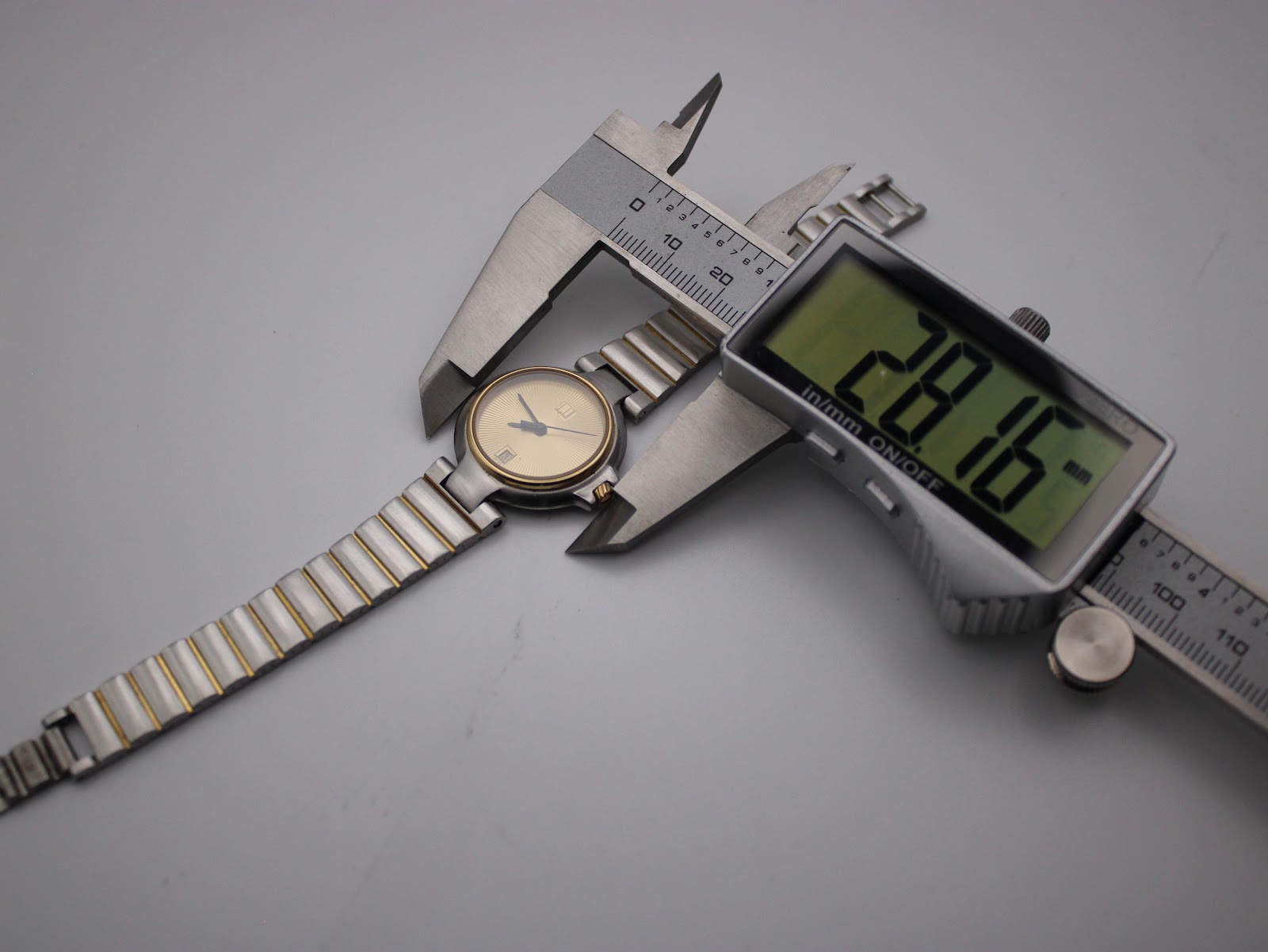 Digital caliper measuring the Dunhill watch case diameter at 28.16 mm.