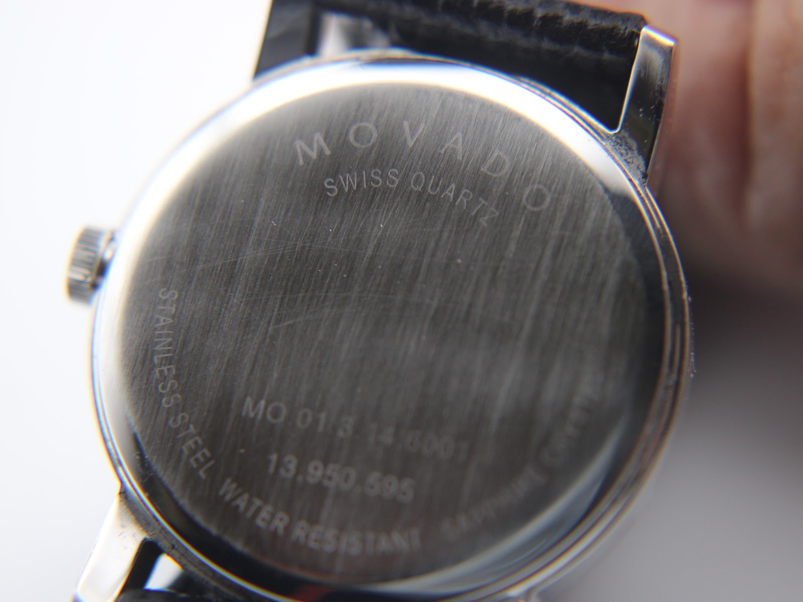 Tilted close-up of the brushed stainless steel case back, with 'Movado swiss quartz' and the model reference number clearly visible.