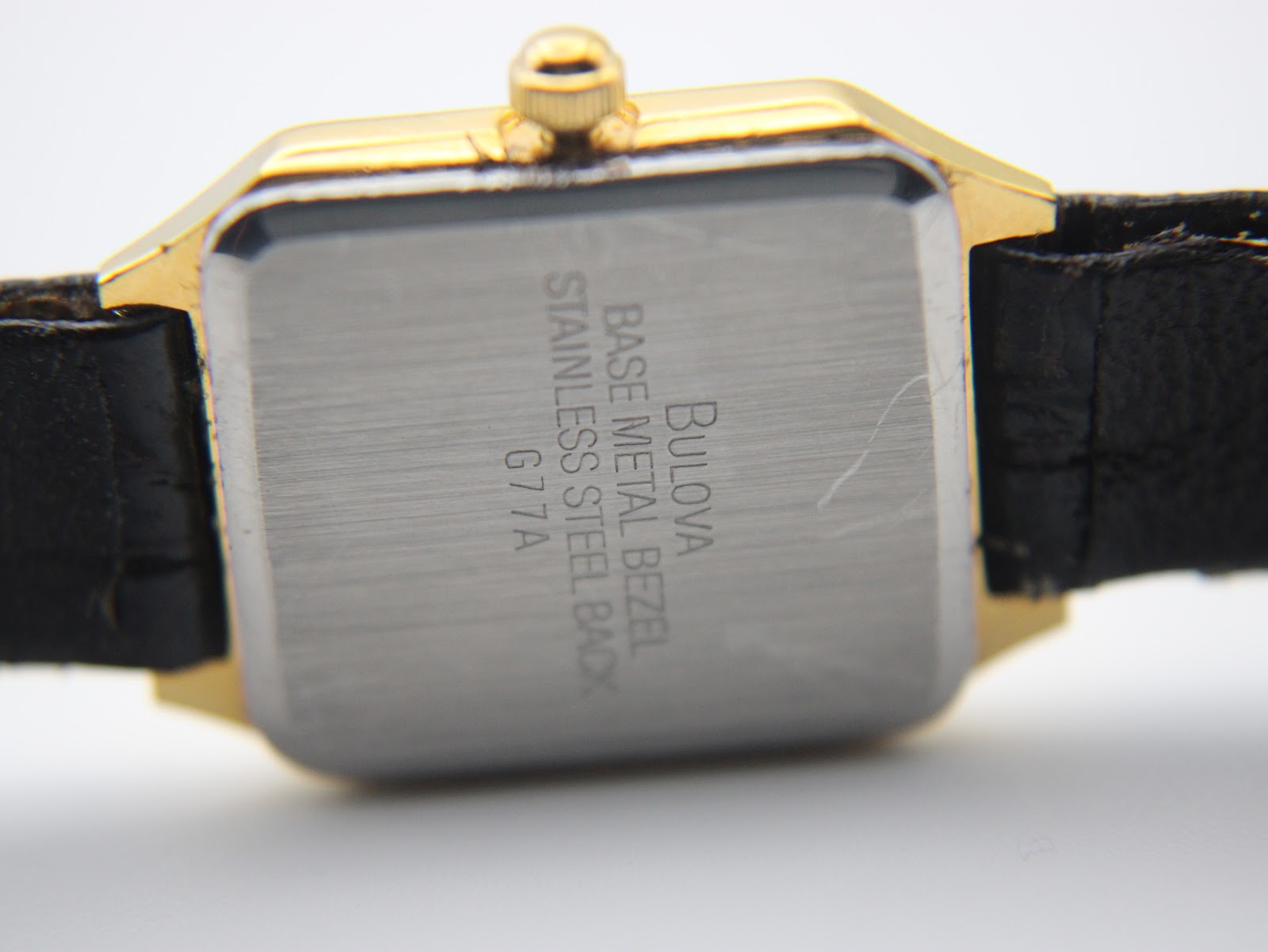 Close-up of the brushed stainless steel case back, clearly showing 'Bulova', 'base metal bezel', and 'stainless steel back G77A' engravings.