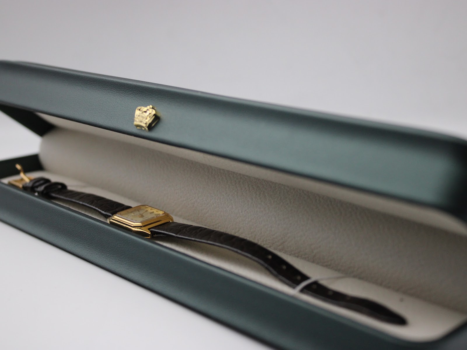 The Bulova watch resting inside an open dark green presentation watch box with a light cream interior.