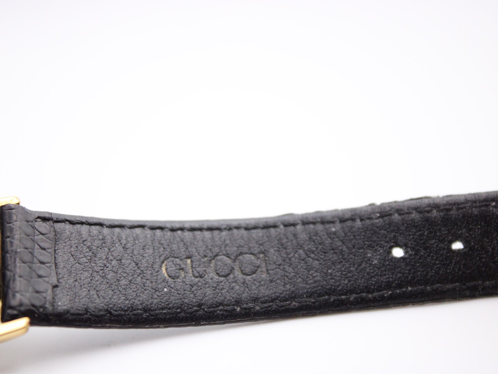 Close-up of the interior of the black leather strap, clearly showing the embossed 'GUCCI' branding.