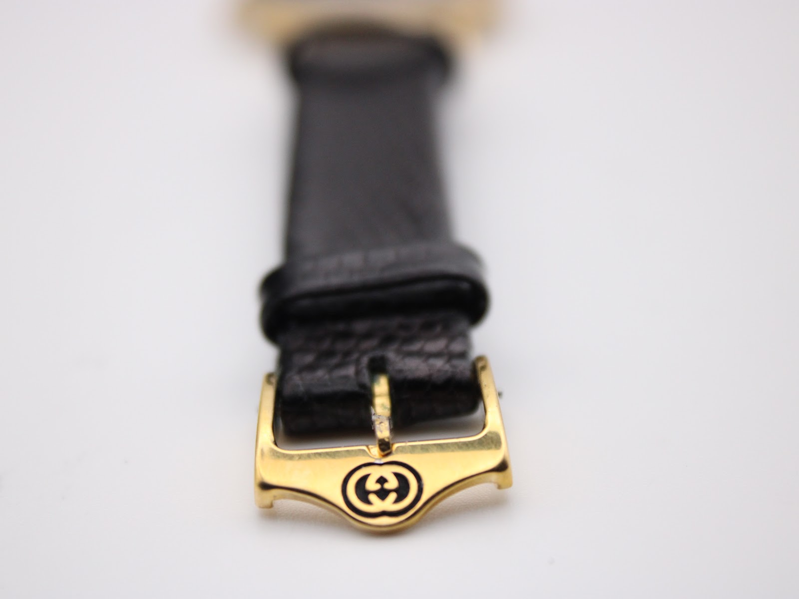 Close-up of the gold-tone buckle, prominently displaying the engraved interlocking Gucci 'G' logo.