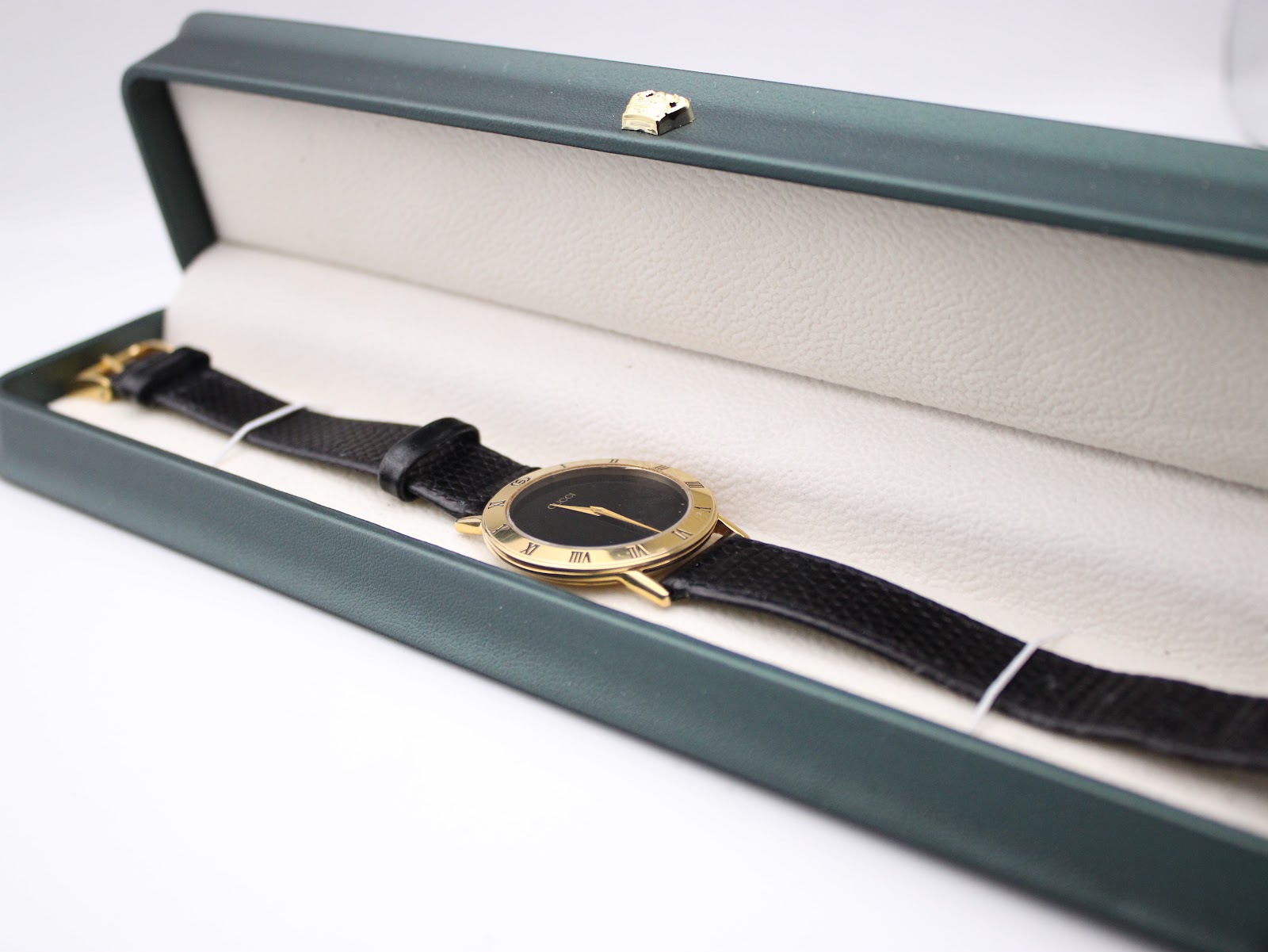 The Gucci 3000.2.M watch presented open in a dark green presentation box with a cream interior lining.