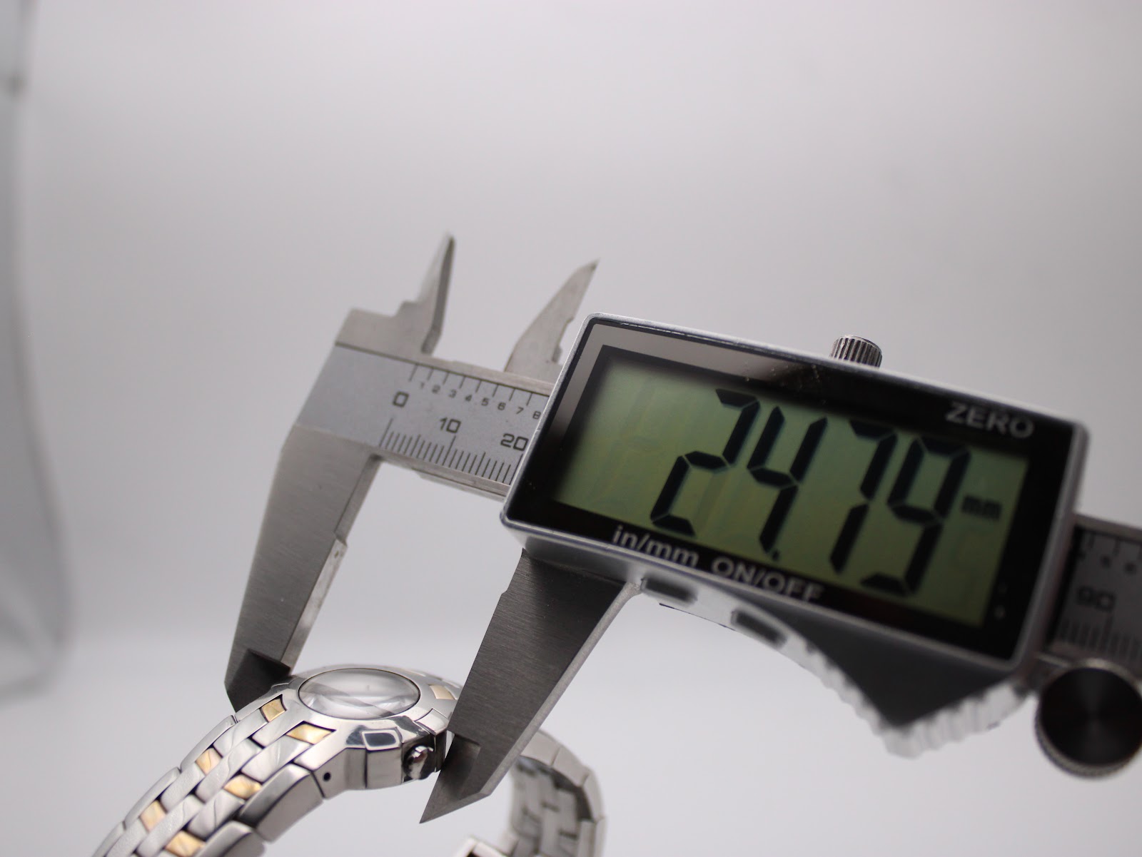 Digital caliper measuring the case diameter of the watch, displaying 24.79mm.