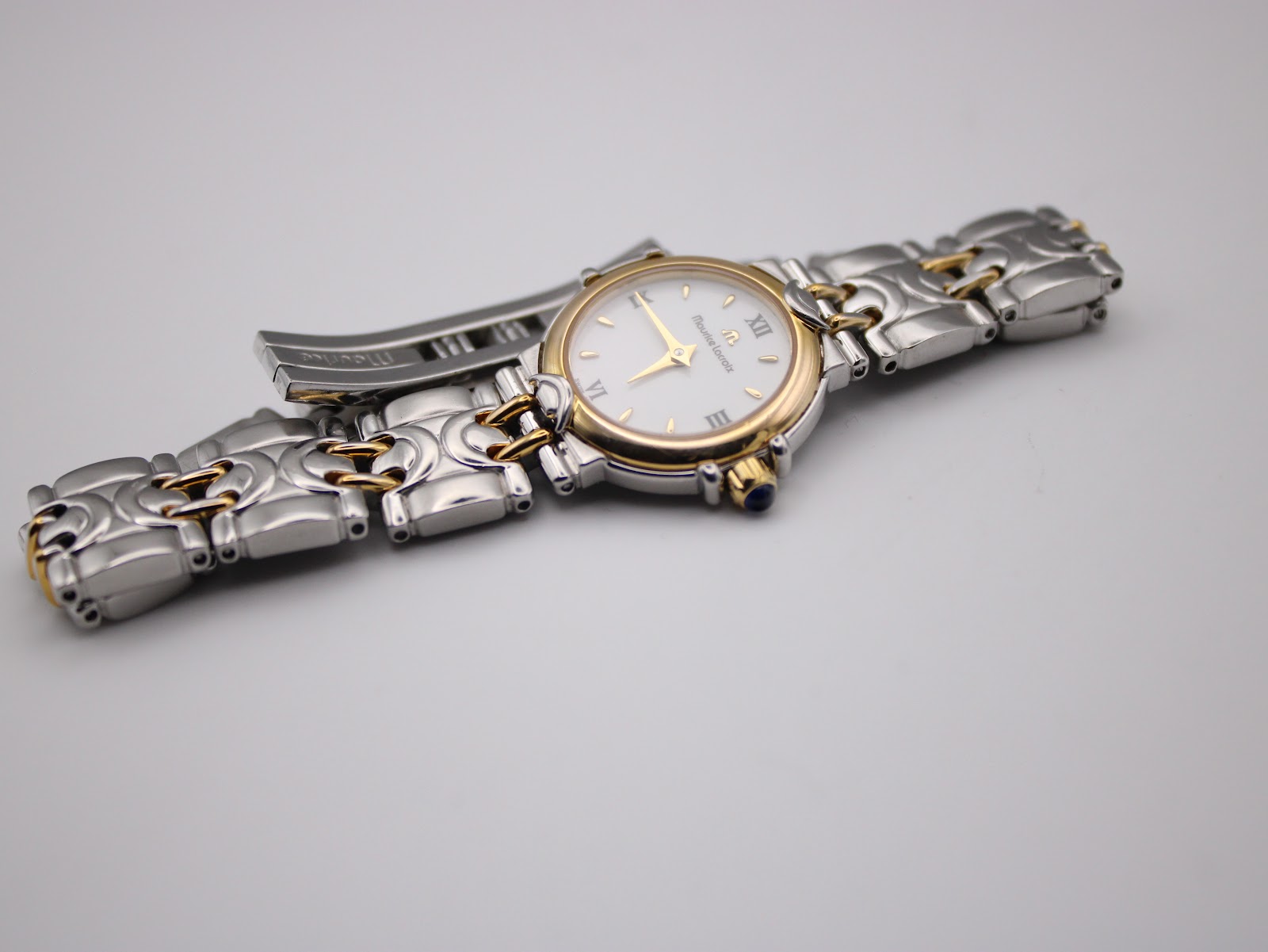 Overhead view of the Maurice Lacroix bi-colour watch with its distinctive bracelet laid flat, showing the white dial and gold details.