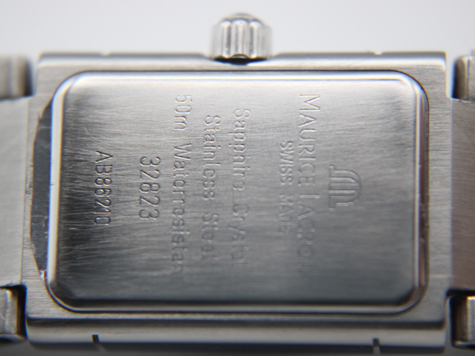 Close-up of the watch's brushed stainless steel case back, showing Maurice Lacroix branding, model number 32823, serial AB86210, 50m water resistance, and sapphire crystal