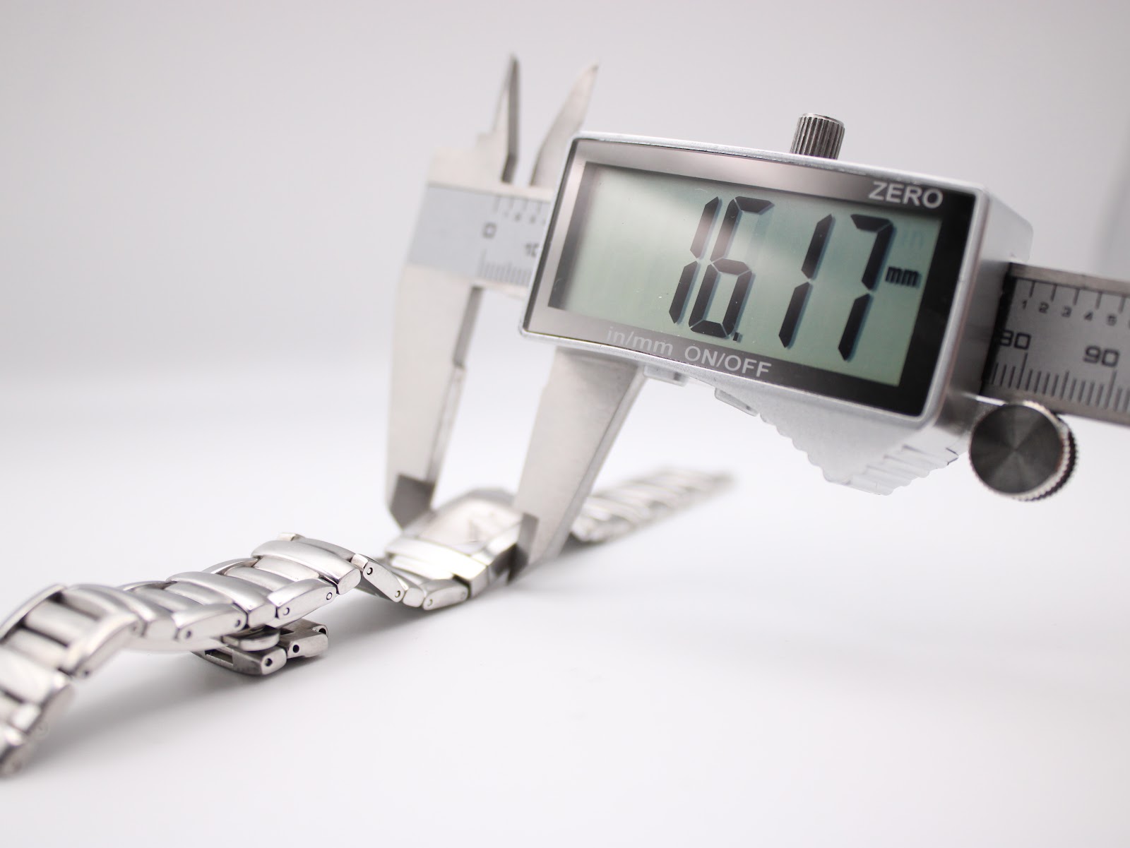 Close-up of a digital caliper measuring the watch case, displaying a width of 16.17 mm