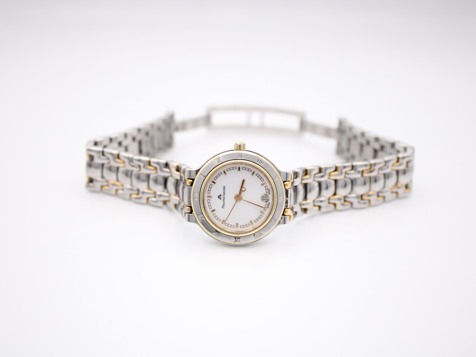 Top-down view of the Maurice Lacroix watch with its two-tone bracelet laid flat, showcasing the white dial and gold Roman numeral bezel.