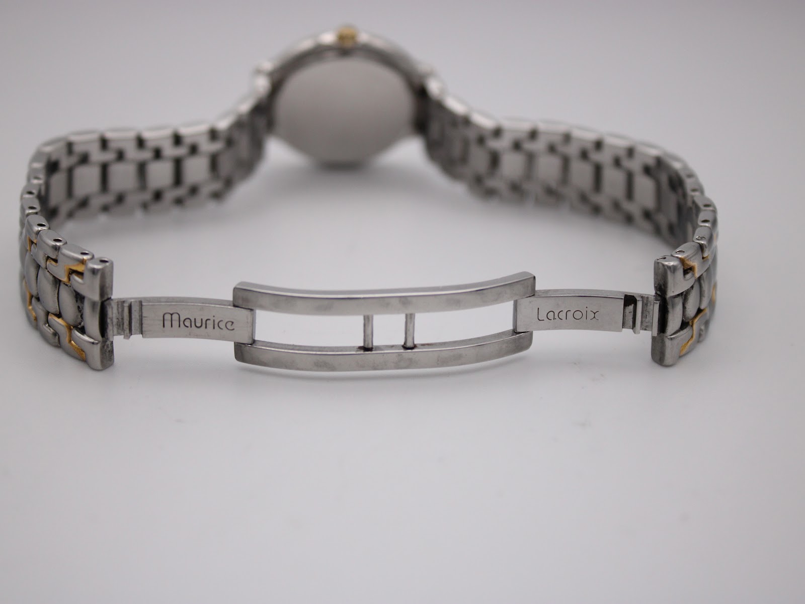 Close-up of the watch's deployment clasp, engraved with "Maurice" on one side and "Lacroix" on the other, showing the inner mechanism.