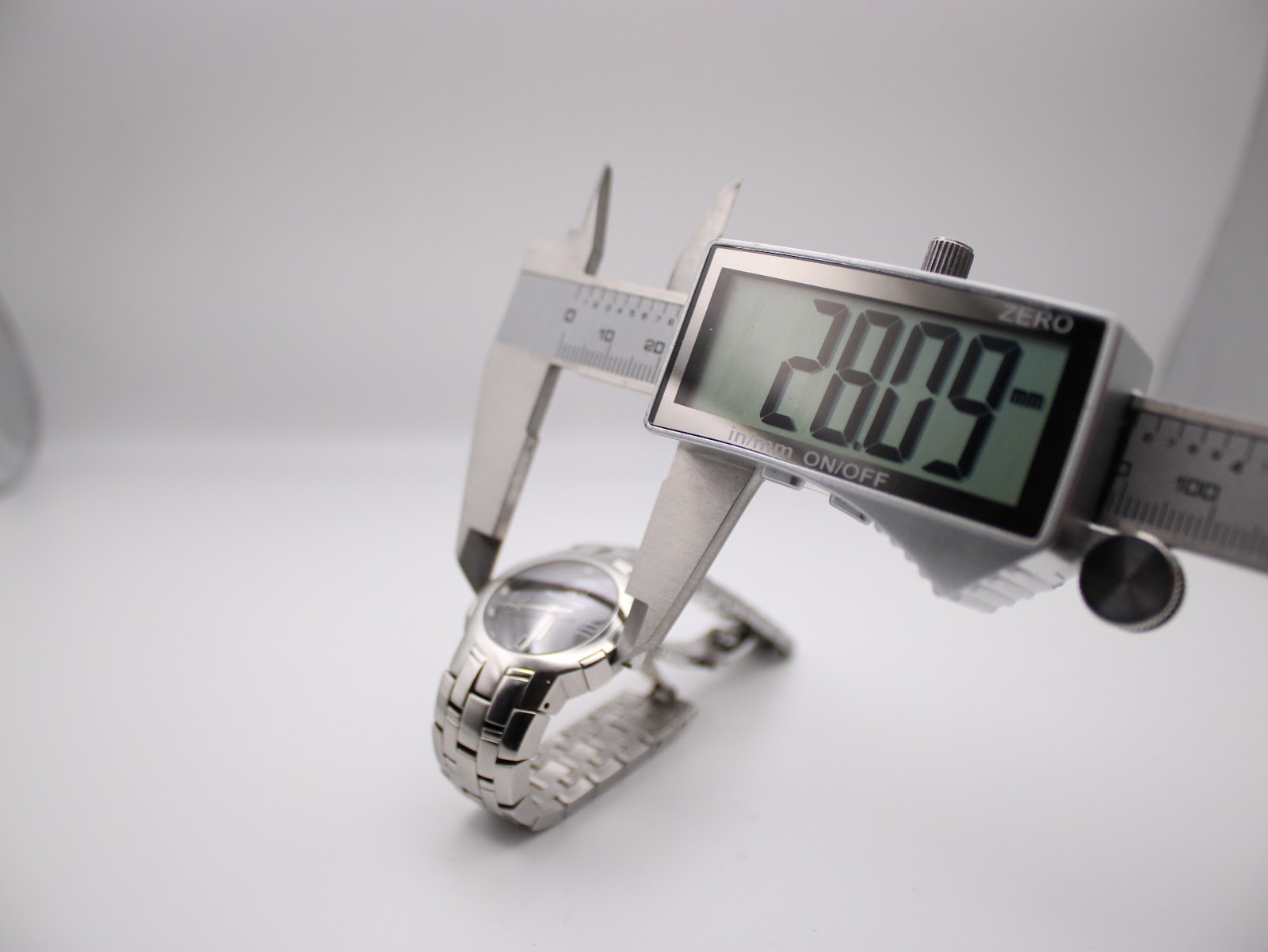 Digital caliper measuring the watch case, showing an exact diameter of 28.09 mm.