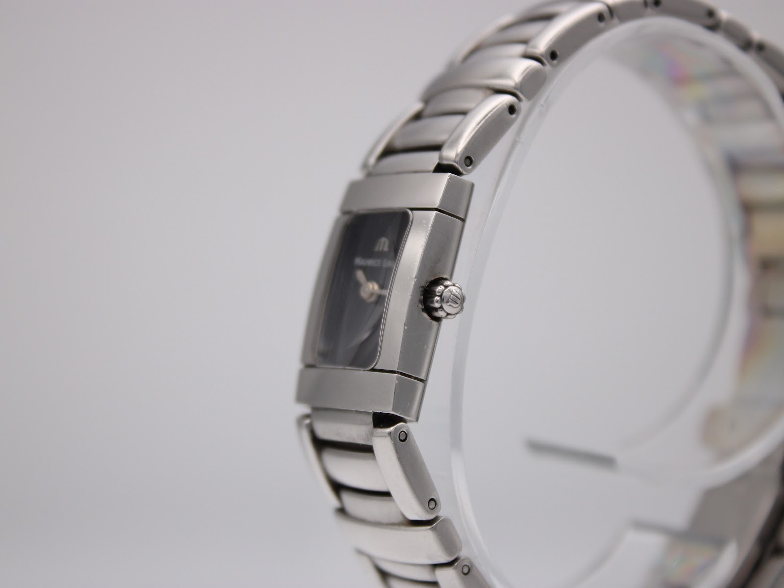 Right side profile view of Maurice Lacroix watch on a display stand, showing the signed crown.
