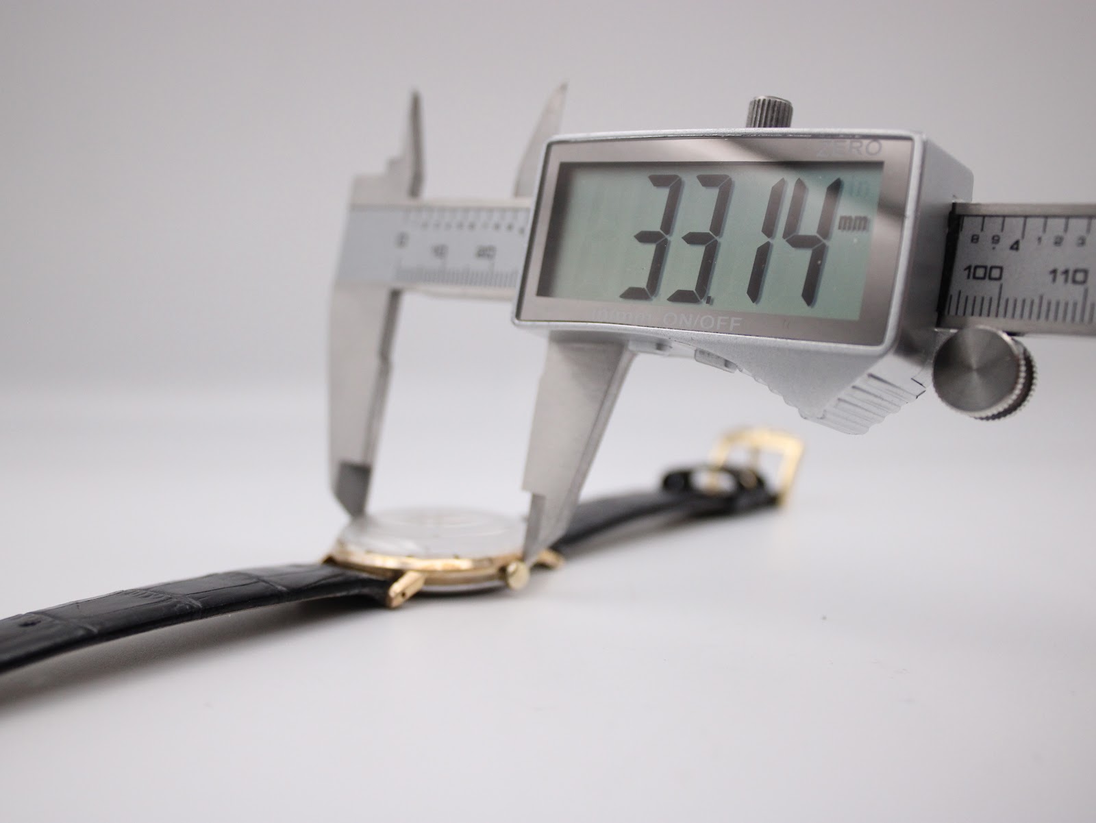 Digital caliper showing the precise case diameter measurement of 33.14mm across the watch case.