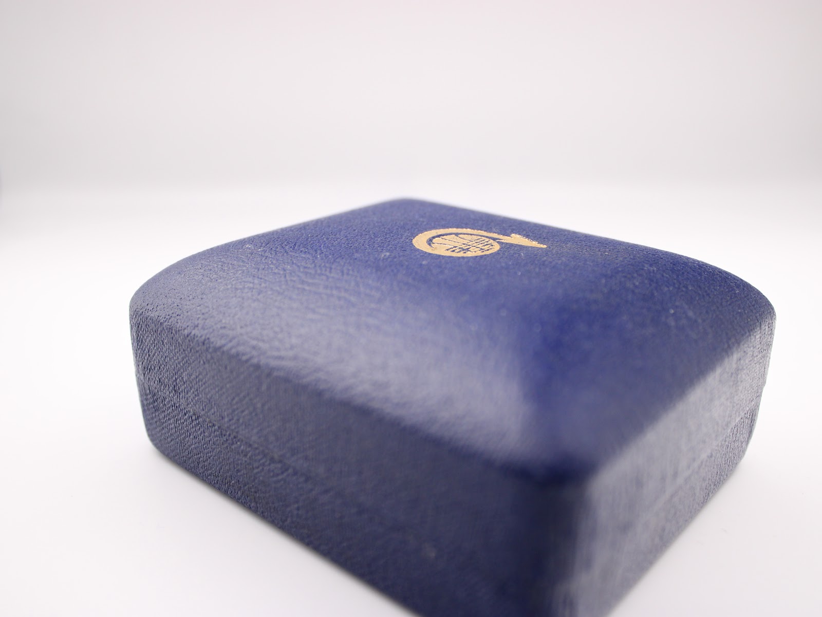 Exterior top view of the vintage navy blue Garrard presentation box with a gold crest.
