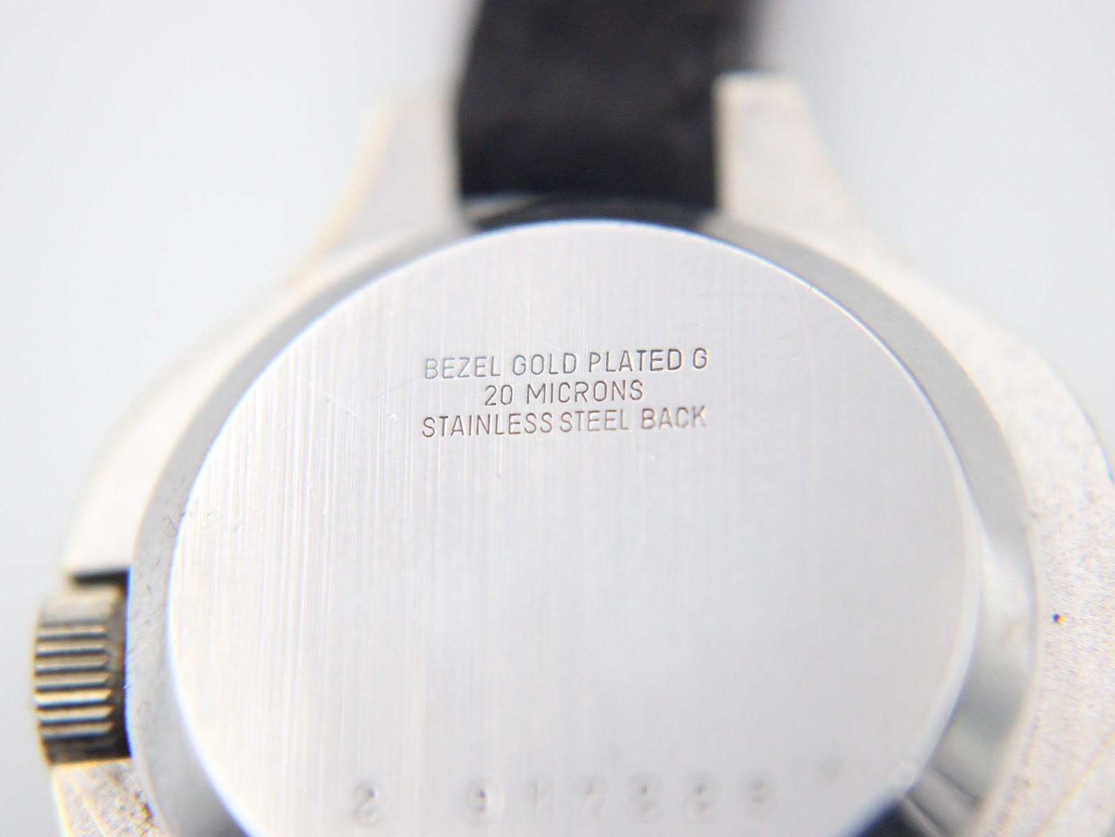 Close-up of the case back engraving "BEZEL GOLD PLATED G 20 MICRONS STAINLESS STEEL BACK".