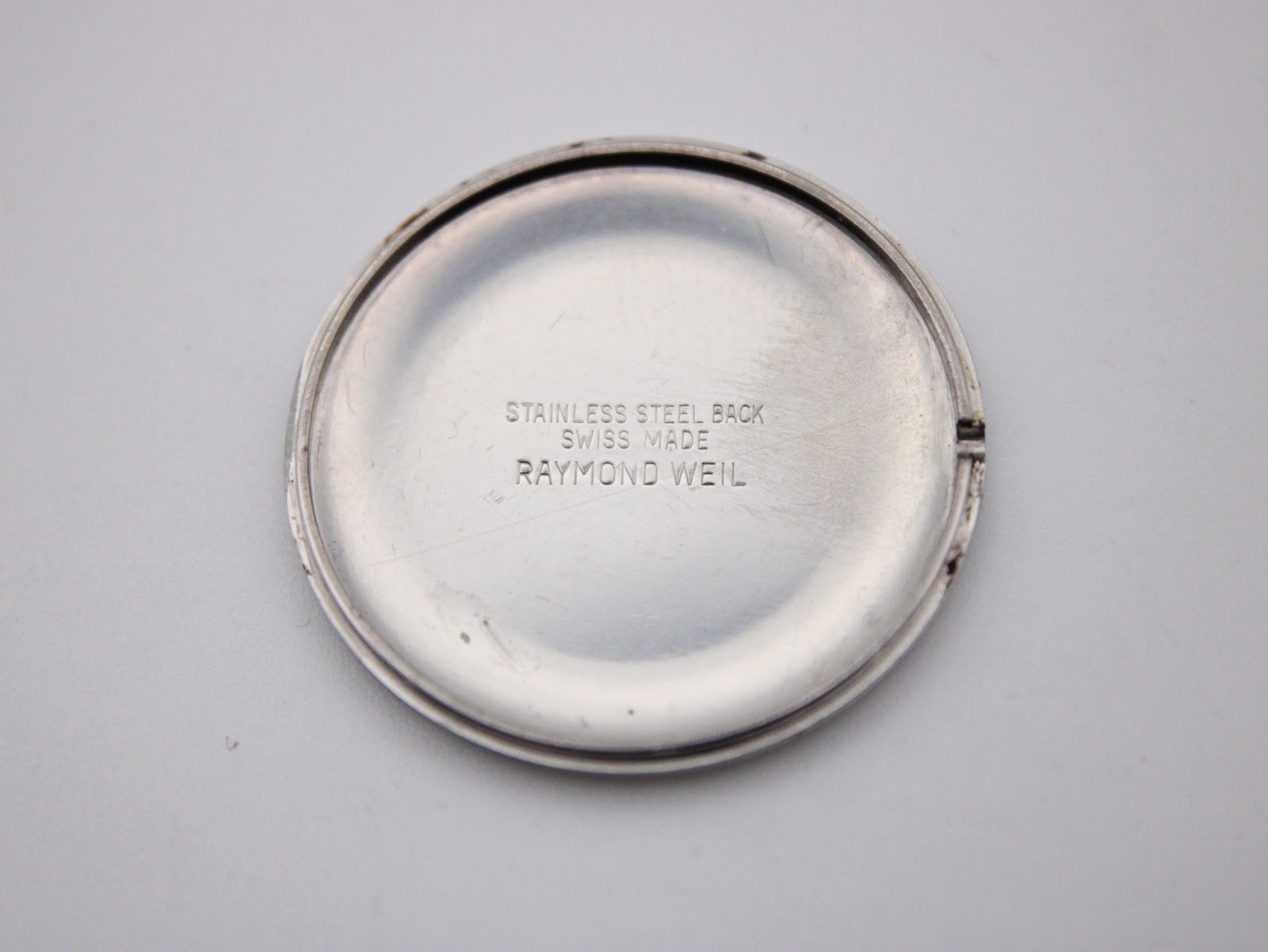 Close-up of the polished stainless steel case back, engraved with "STAINLESS STEEL BACK SWISS MADE RAYMOND WEIL".
