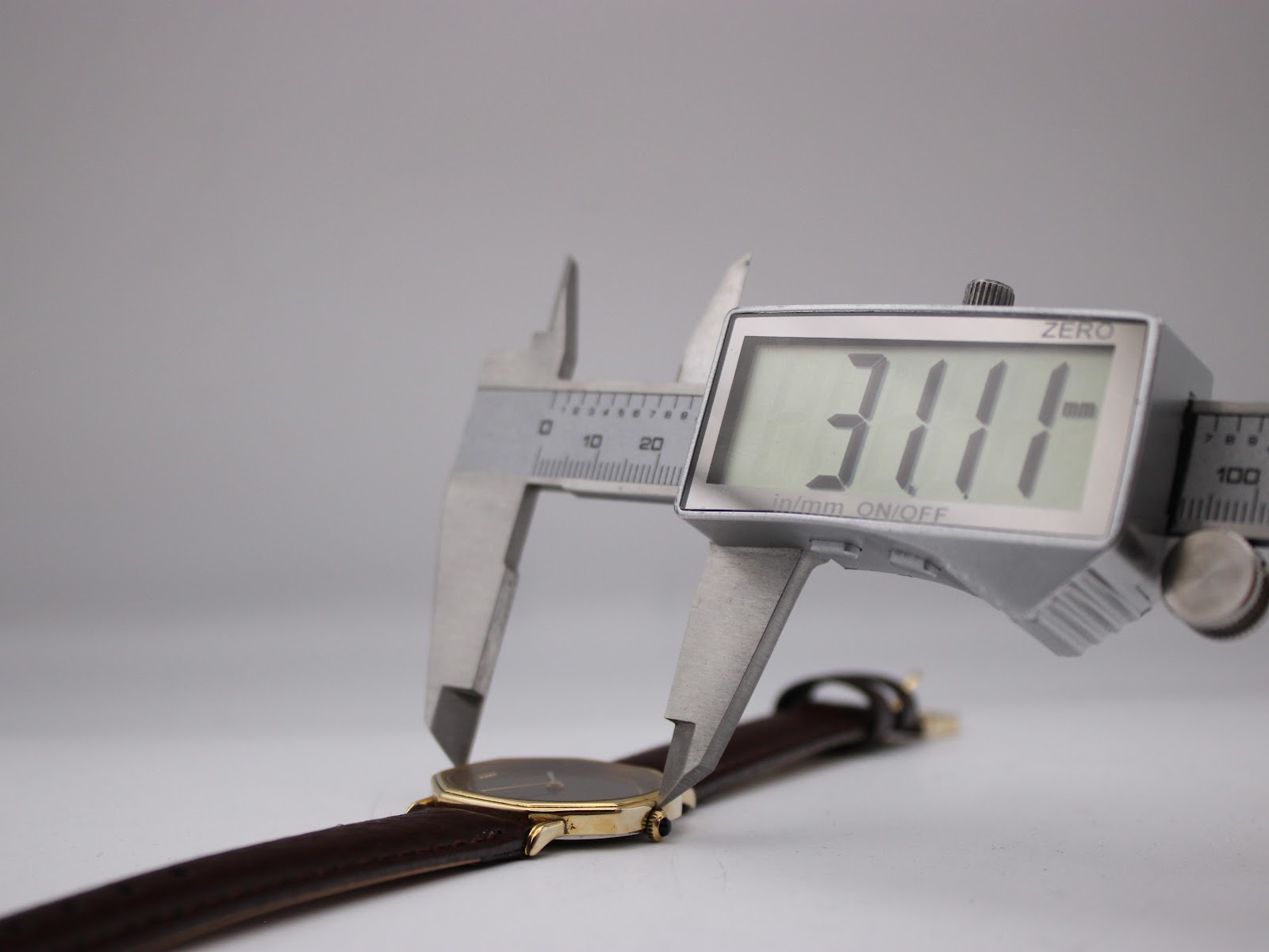 Digital caliper measuring the case diameter of the watch, displaying a precise reading of 31.11mm.