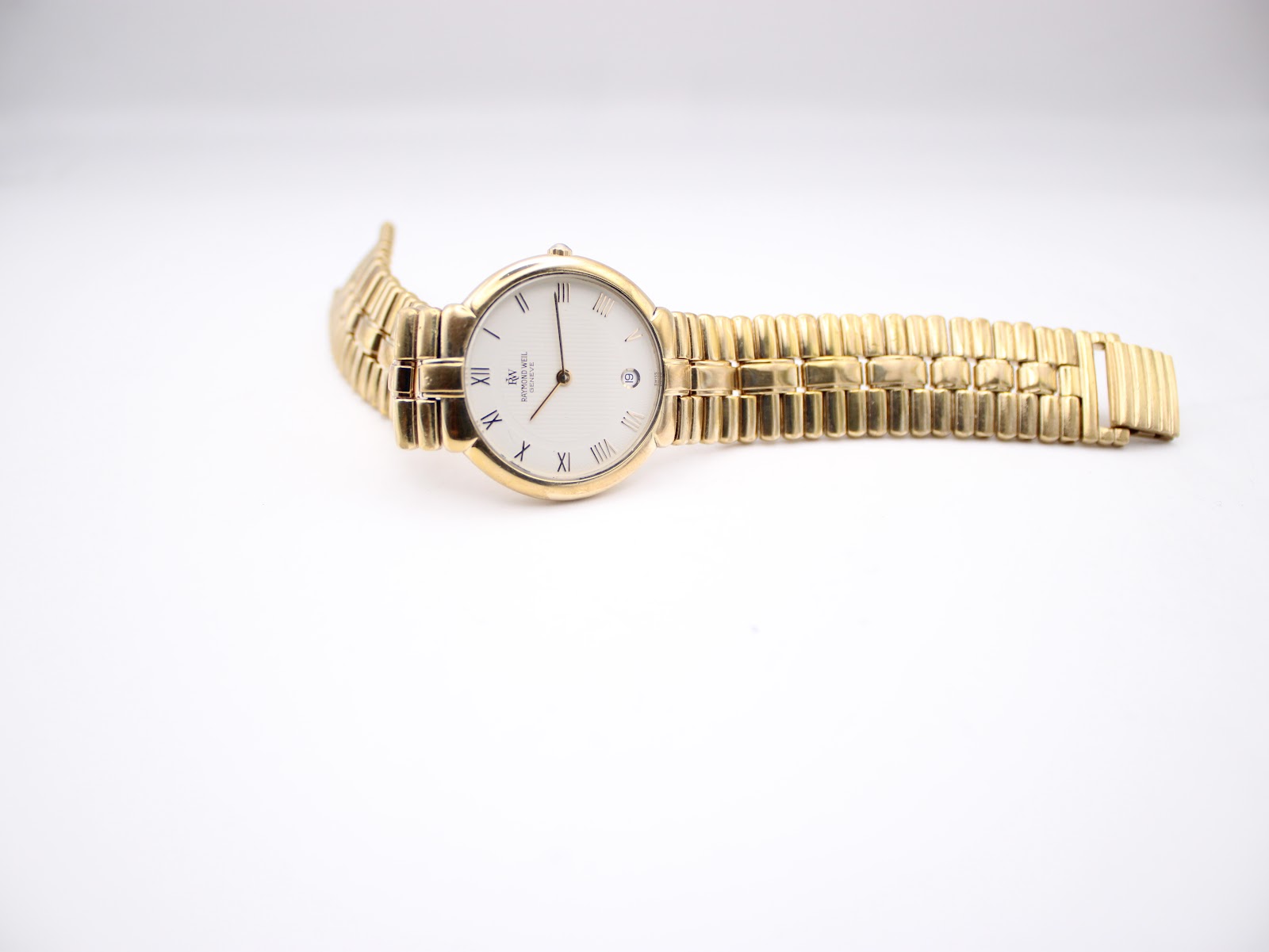 Overhead view of the Raymond Weil watch laid flat on a white surface, displaying the full length of the gold bracelet.