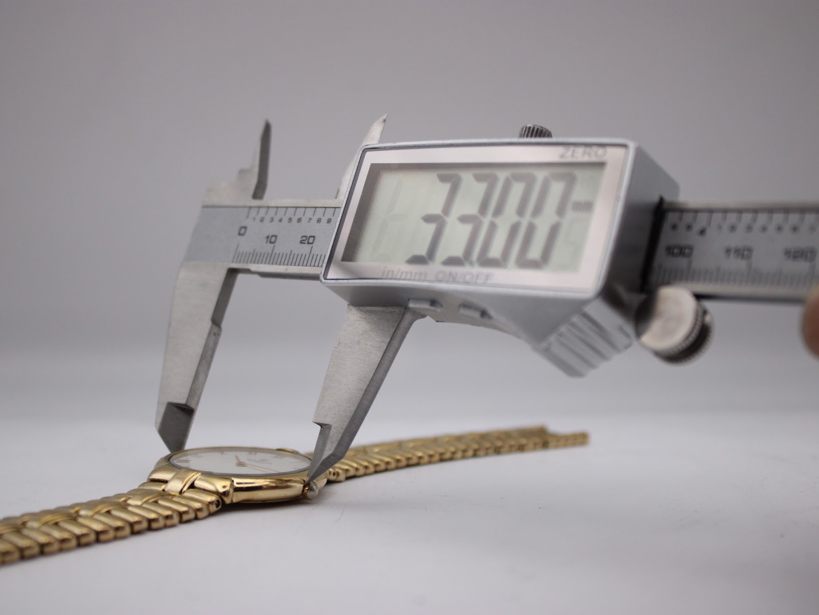 Digital caliper measuring the case diameter of the Raymond Weil watch, displaying 33.00mm.