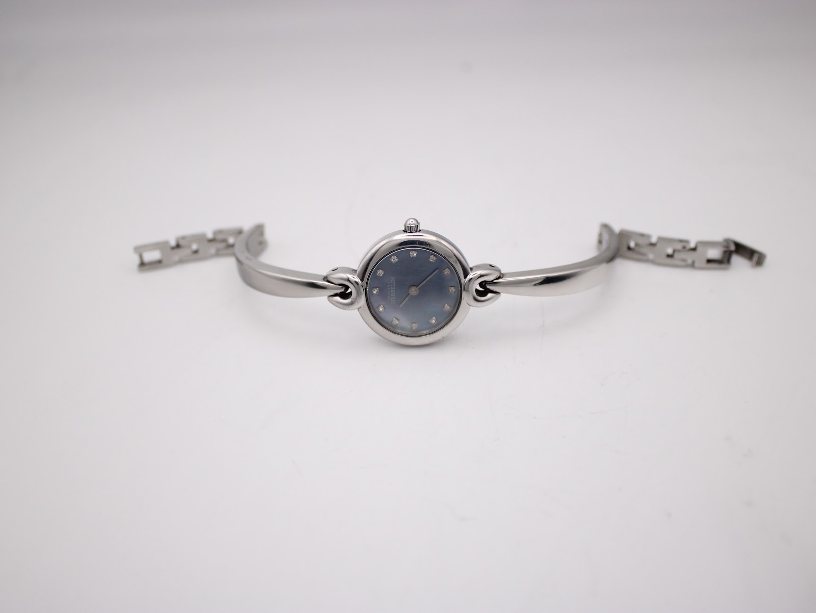 Full view of the Michel Herbelin watch lying flat, showing the integrated bangle bracelet with its clasp unfastened.