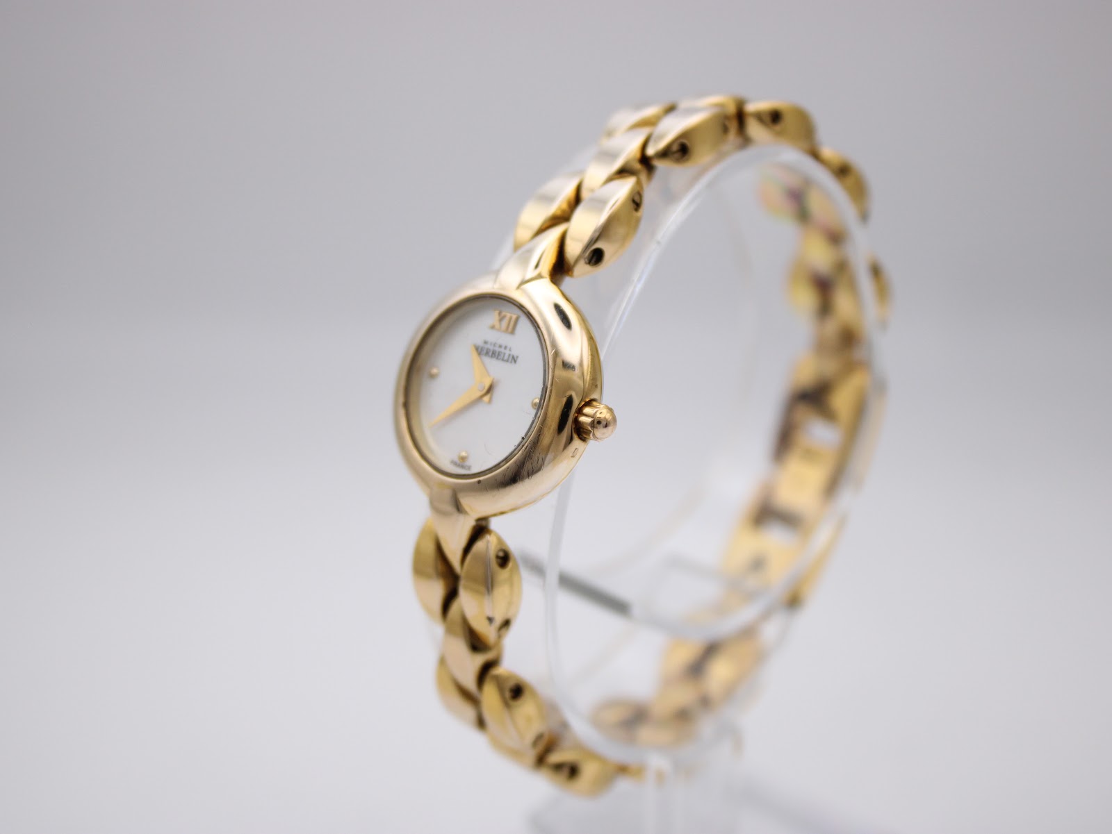 Angled view of Michel Herbelin ladies watch from the right, showcasing the gold-plated case and bracelet, with the white dial visible.