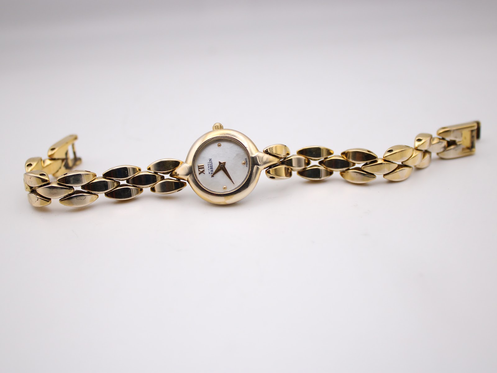 Full length top-down view of the Michel Herbelin Paris watch laid flat, displaying the entire gold-plated integrated bracelet and the small round watch head.