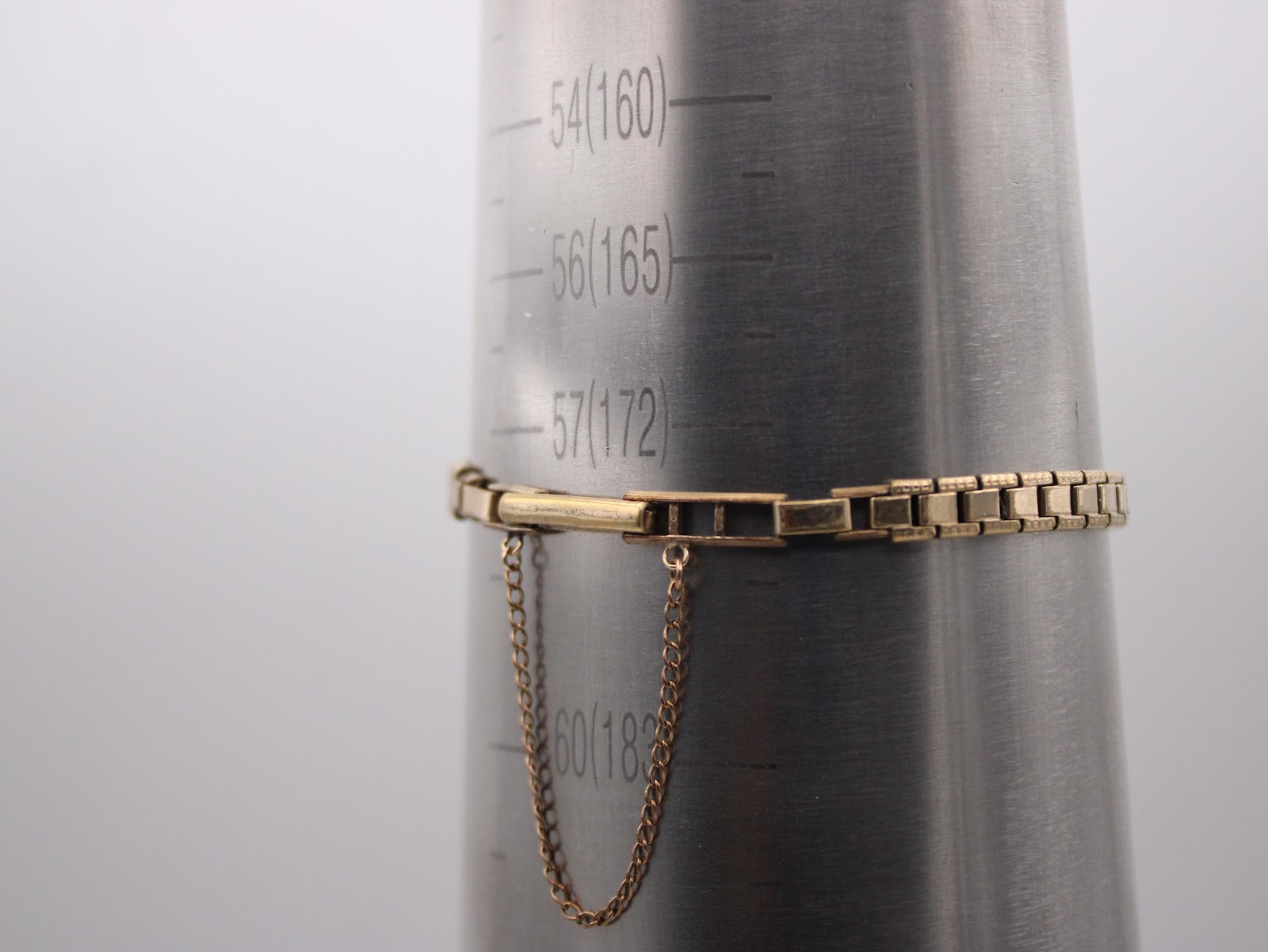 Gold integrated bracelet with safety chain on a wrist sizing gauge, showing 17.2cm measurement.